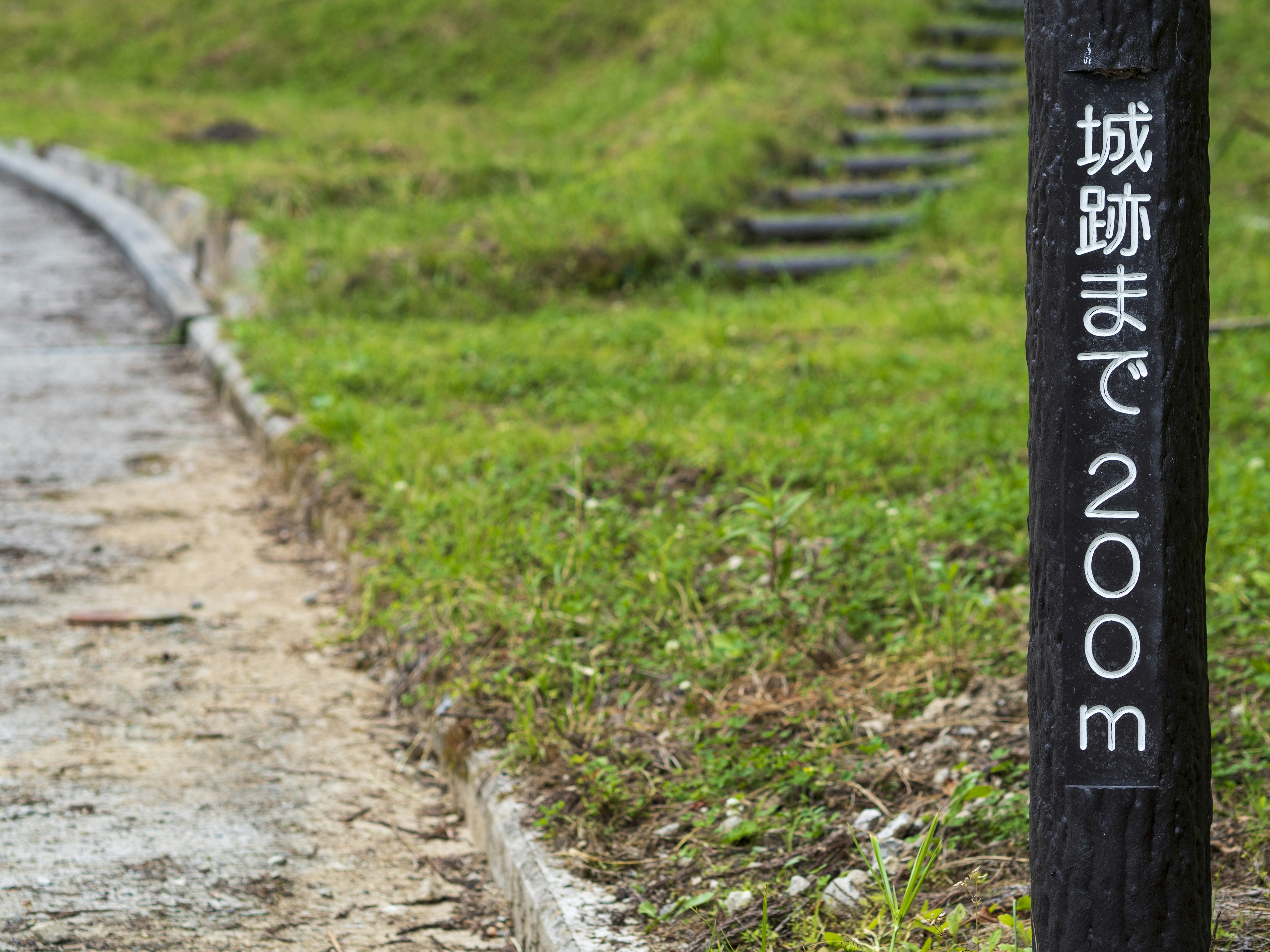 城跡まで200メートルの標識がある緑の道