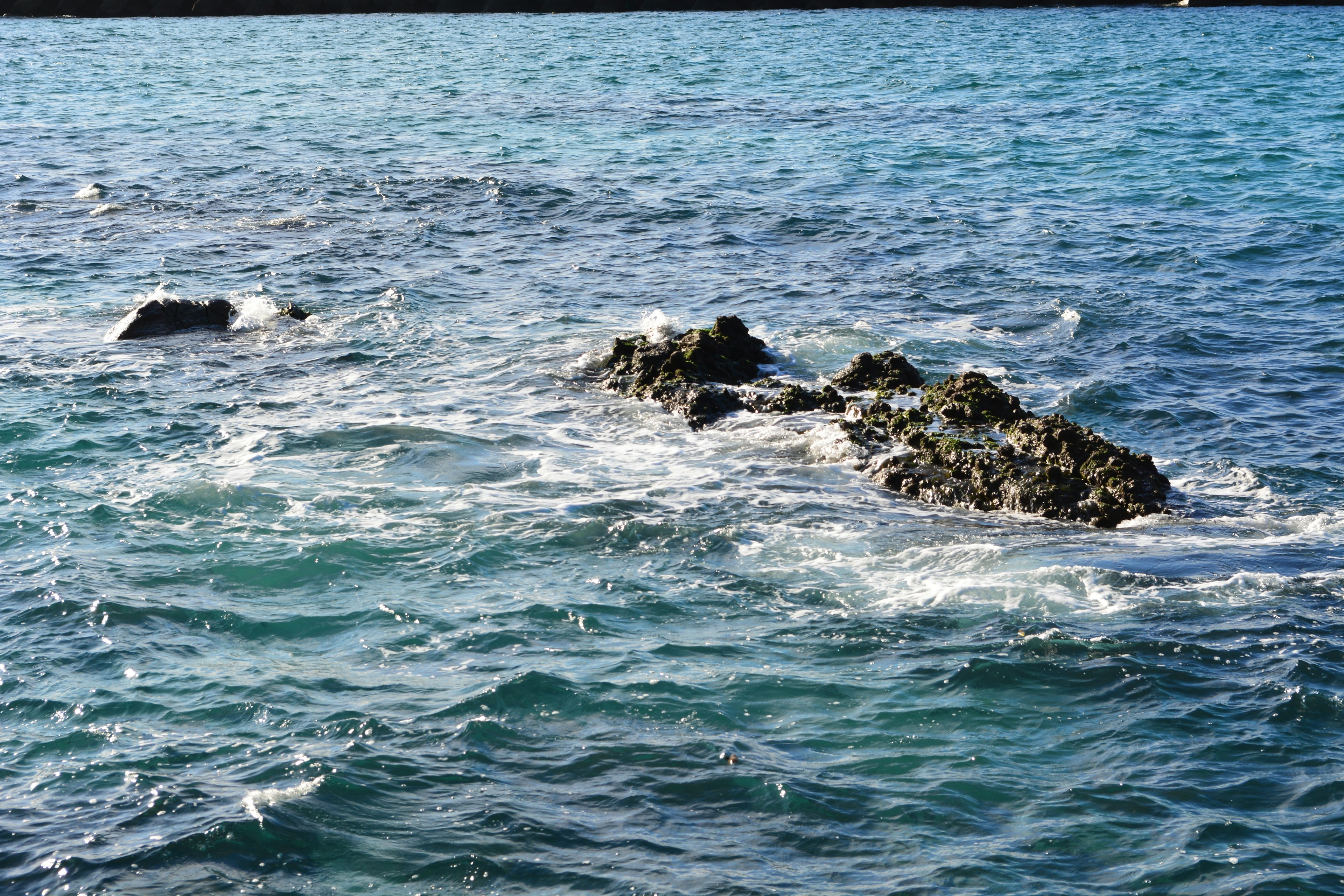 Rocky outcrop surrounded by turquoise waves