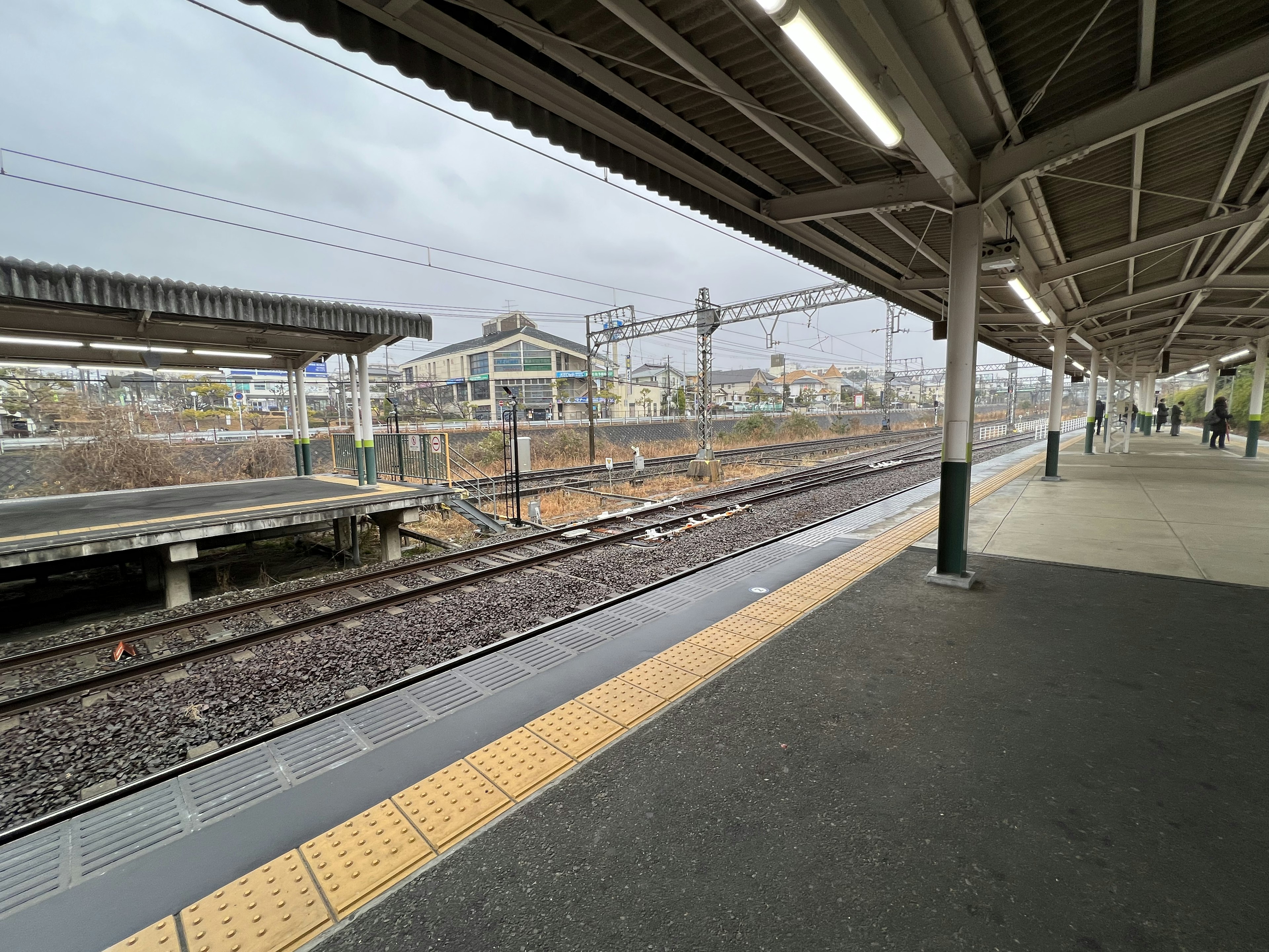 Train station platform with railway tracks under cloudy sky