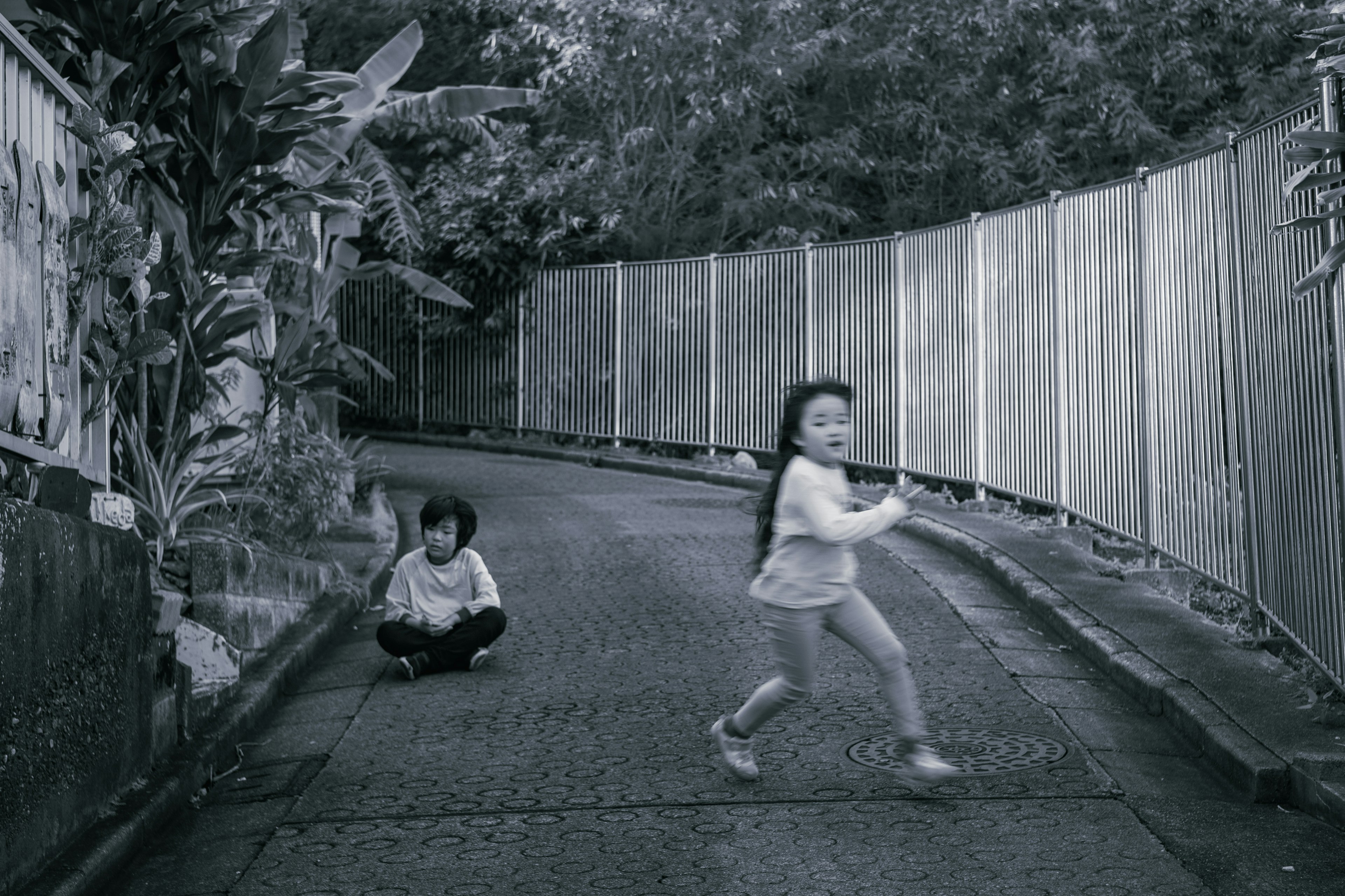 Two children in a black and white scene A young girl running A boy sitting