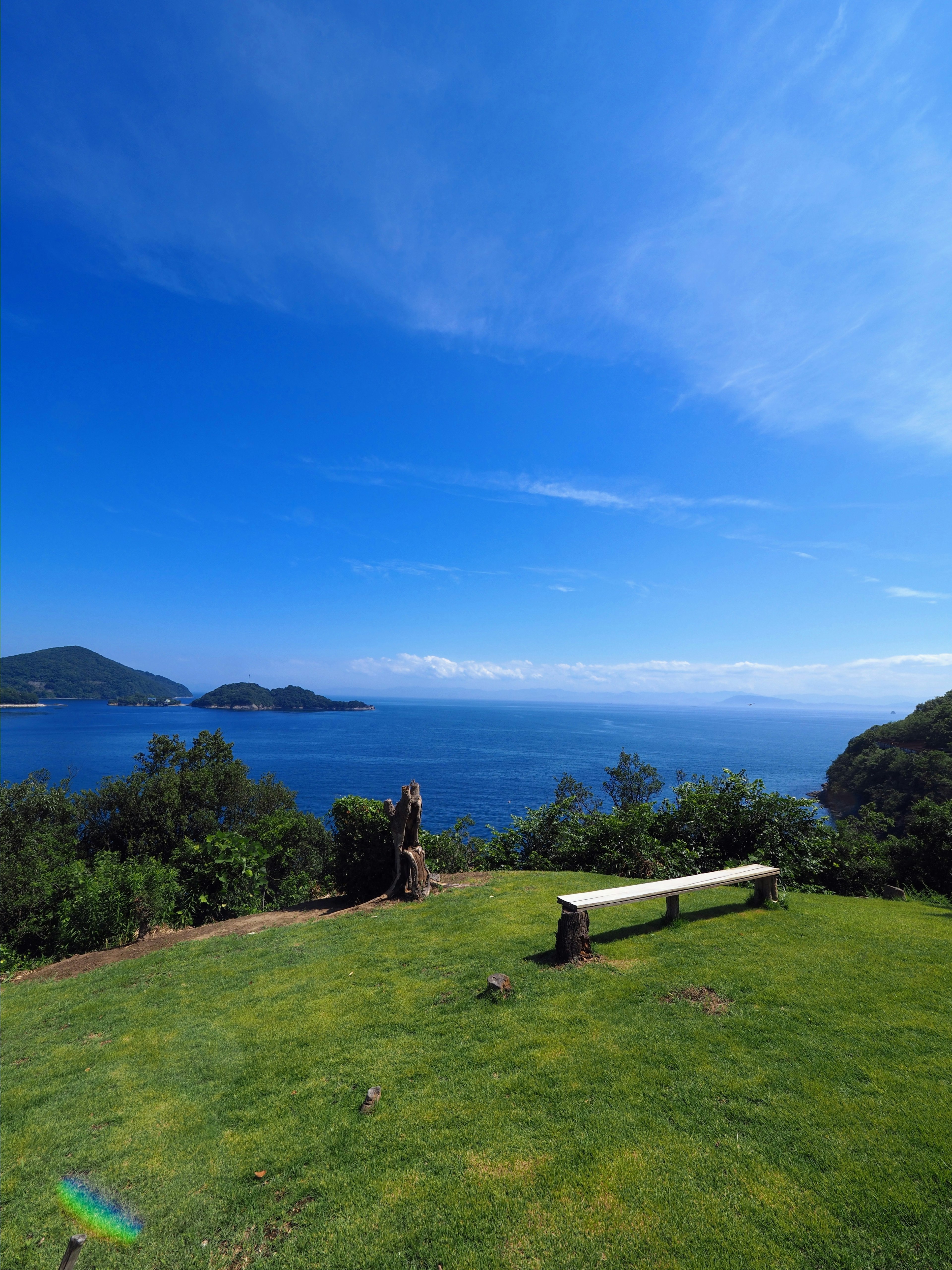 Schöne Landschaft mit blauem Himmel und Ozean grünem Gras und Bank