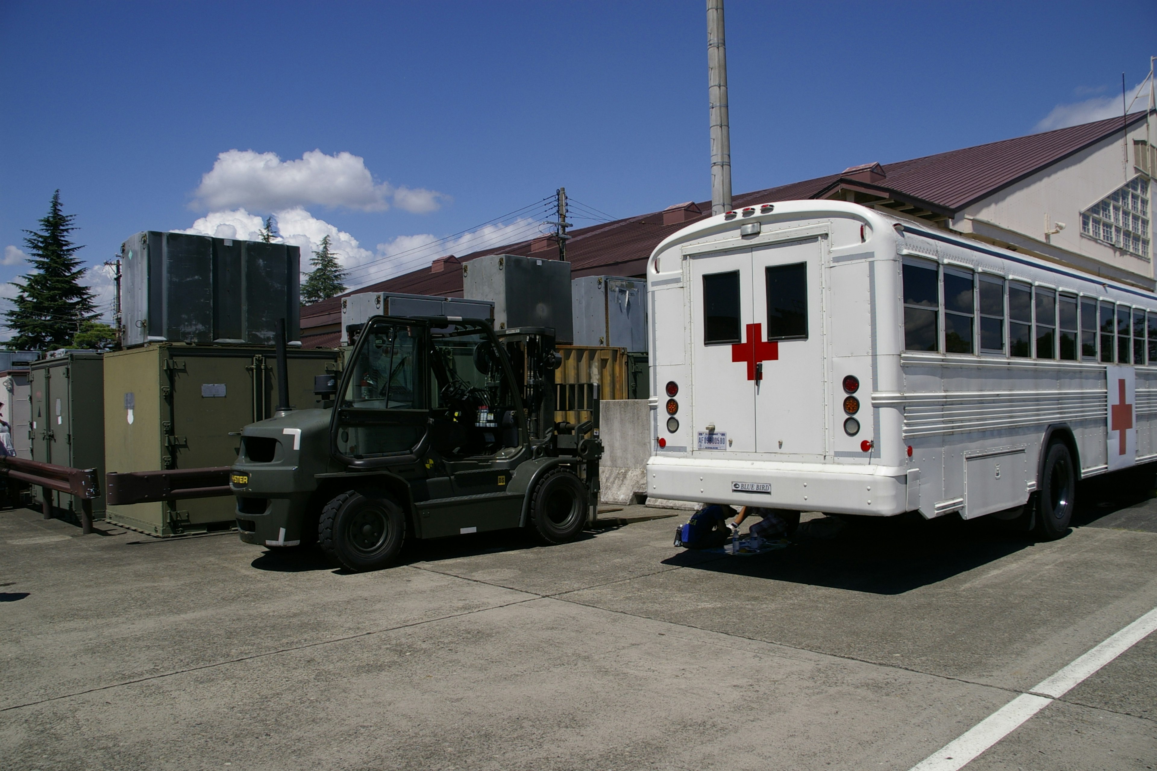 A white ambulance bus and military vehicle parked outdoors