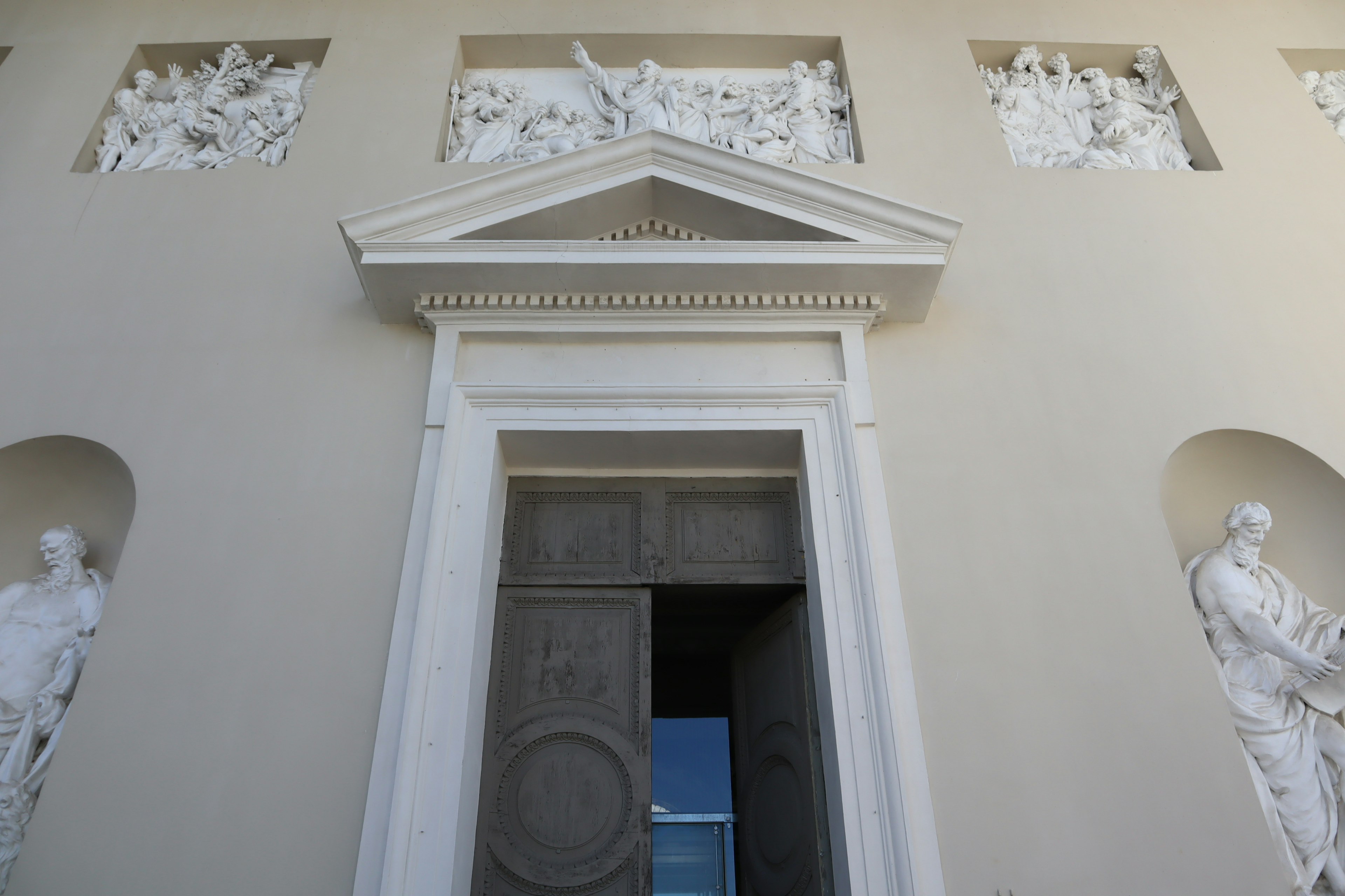 Detail of the main entrance of a building featuring white sculptures