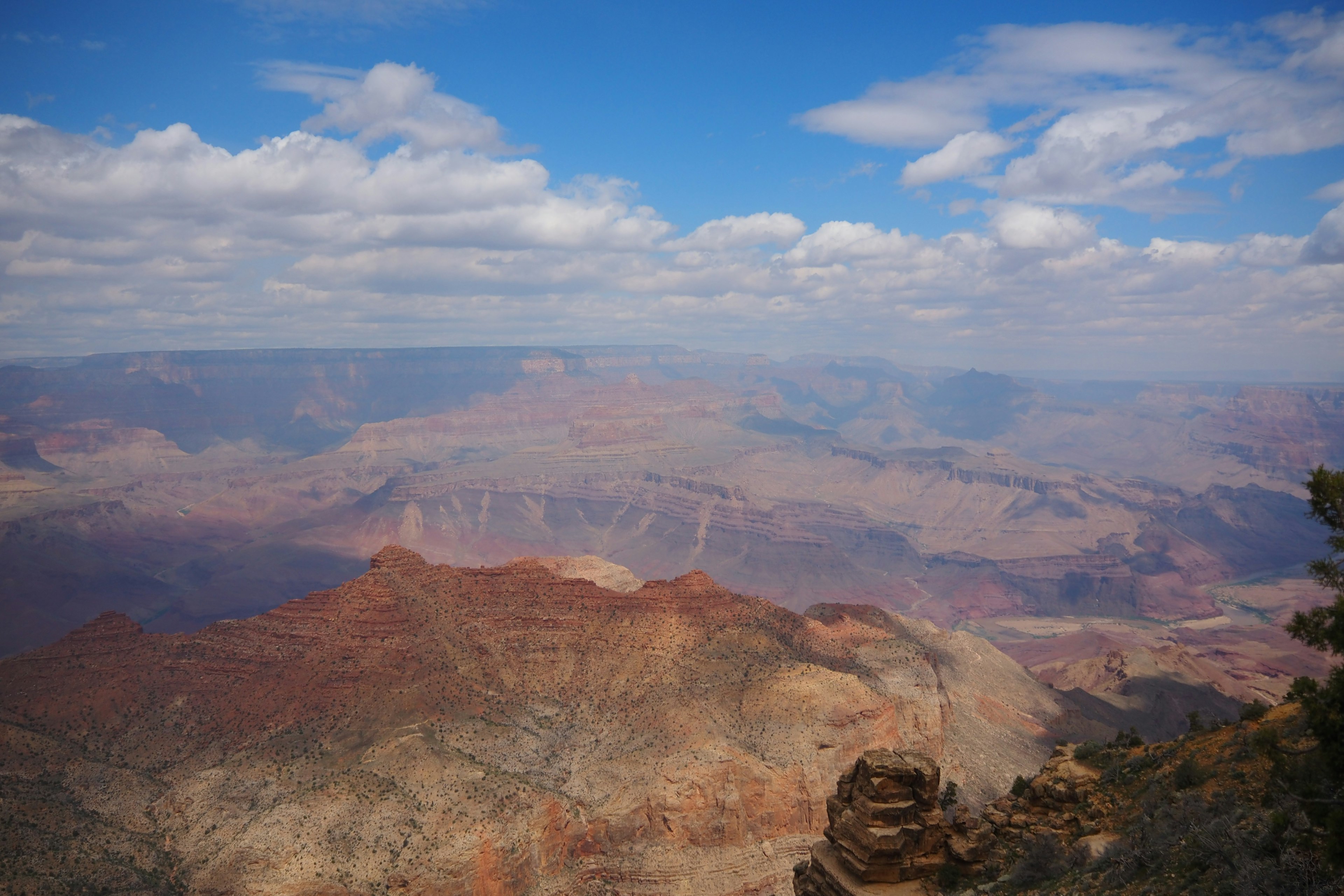 Expansive view of the Grand Canyon with blue sky and white clouds