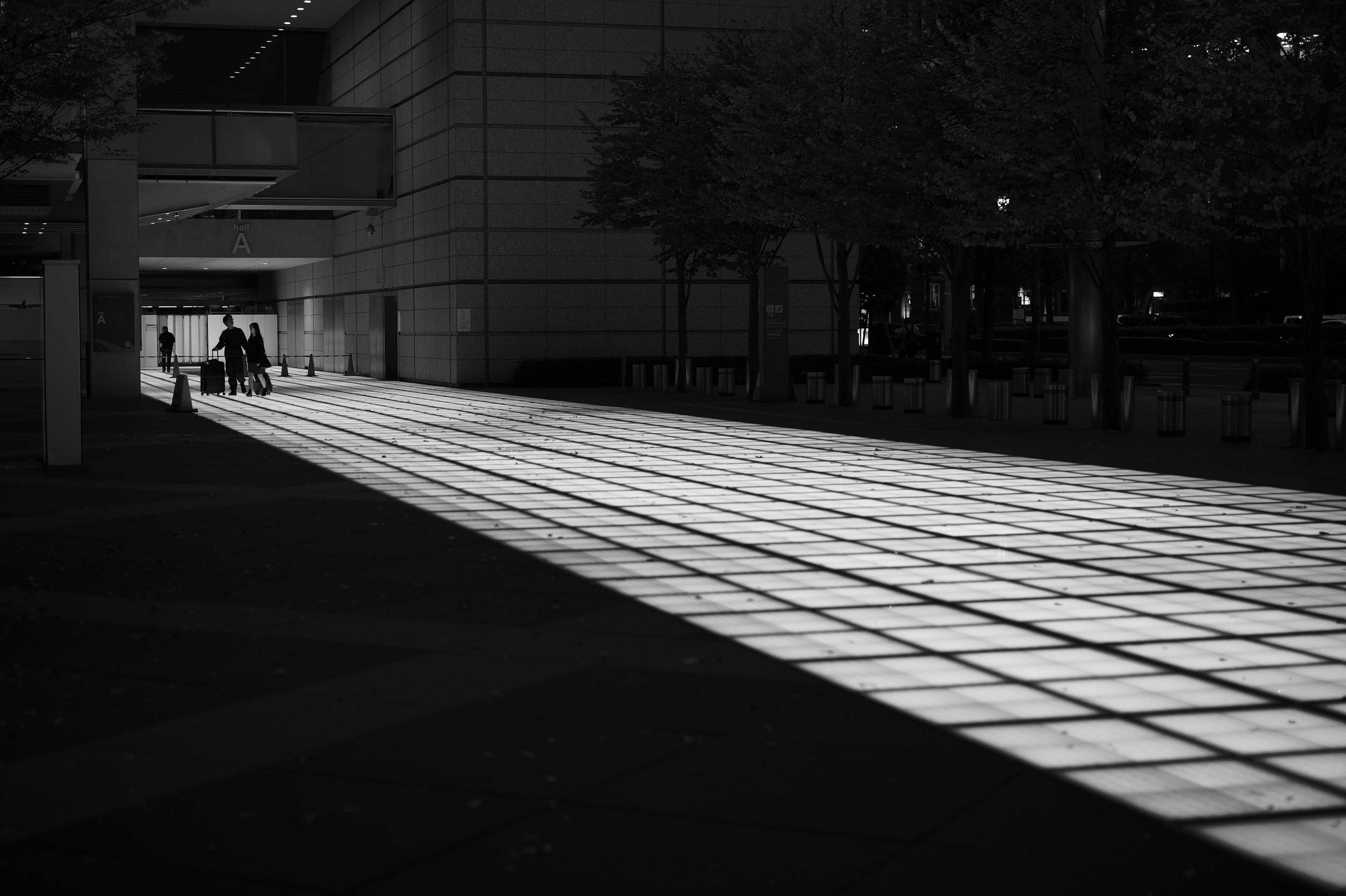 Paesaggio urbano in bianco e nero con marciapiede illuminato persone che camminano