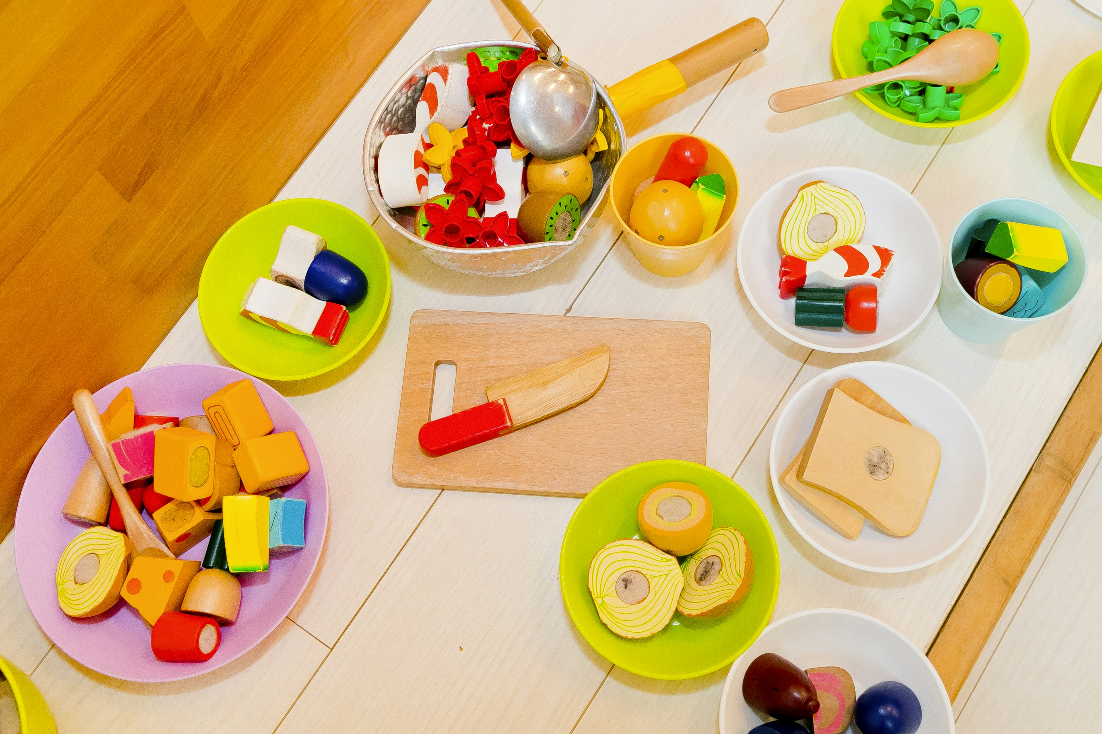 Artículos de comida de juguete coloridos dispuestos en cuencos y platos en un área de juego