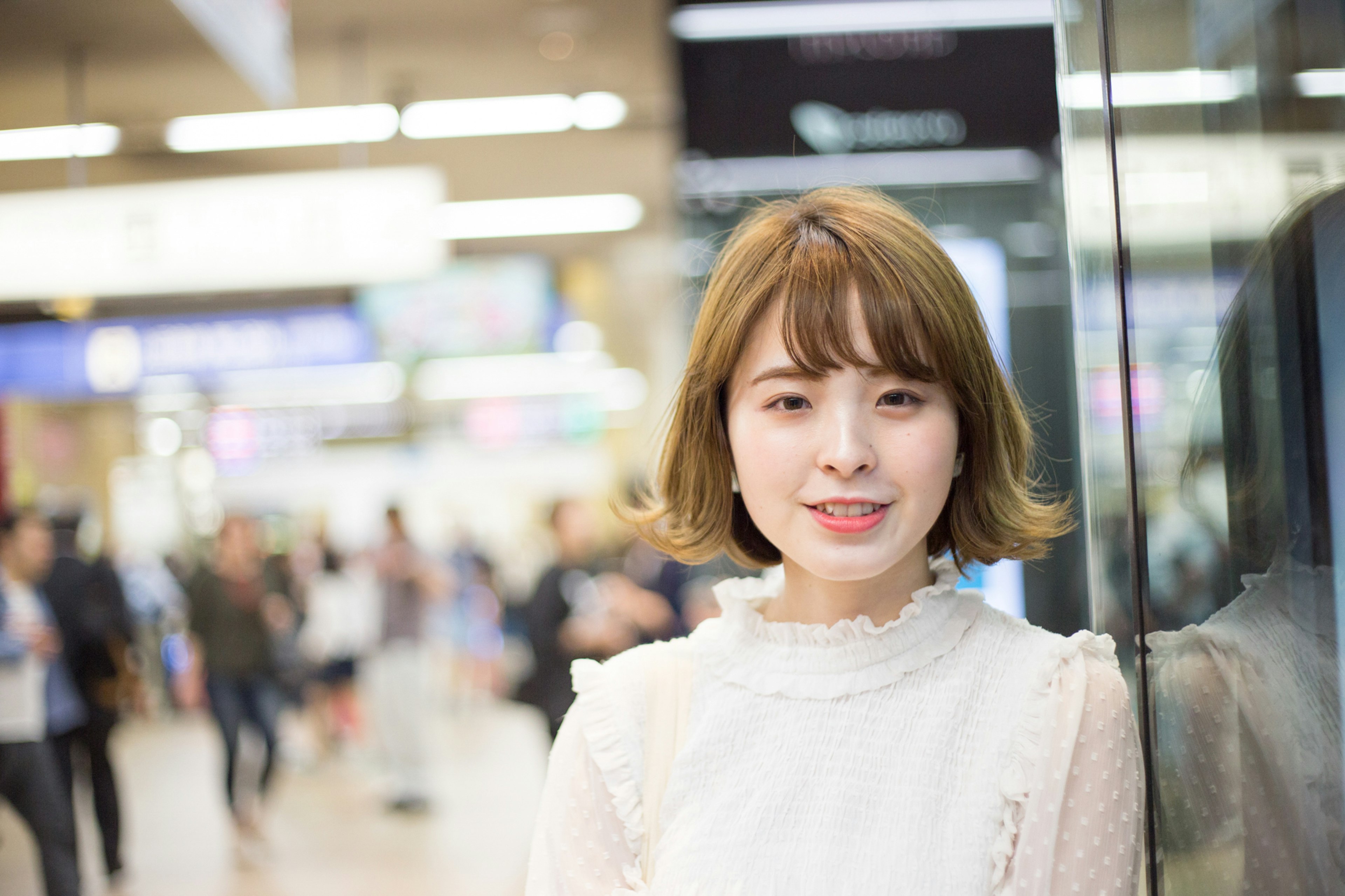 Young woman smiling at a train station with people in the background