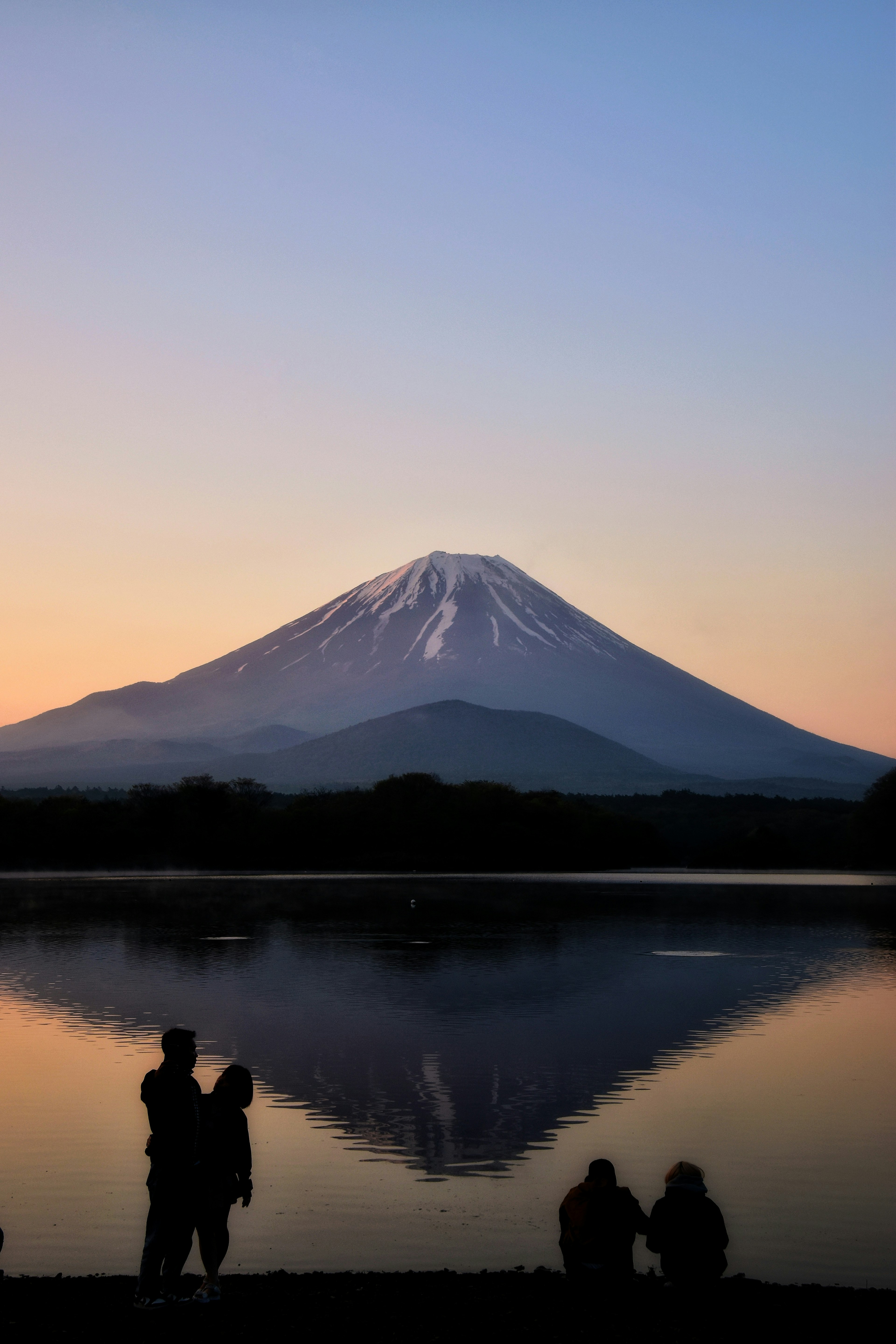 Siluet pasangan di latar belakang matahari terbenam yang indah dan pantulan Gunung Fuji