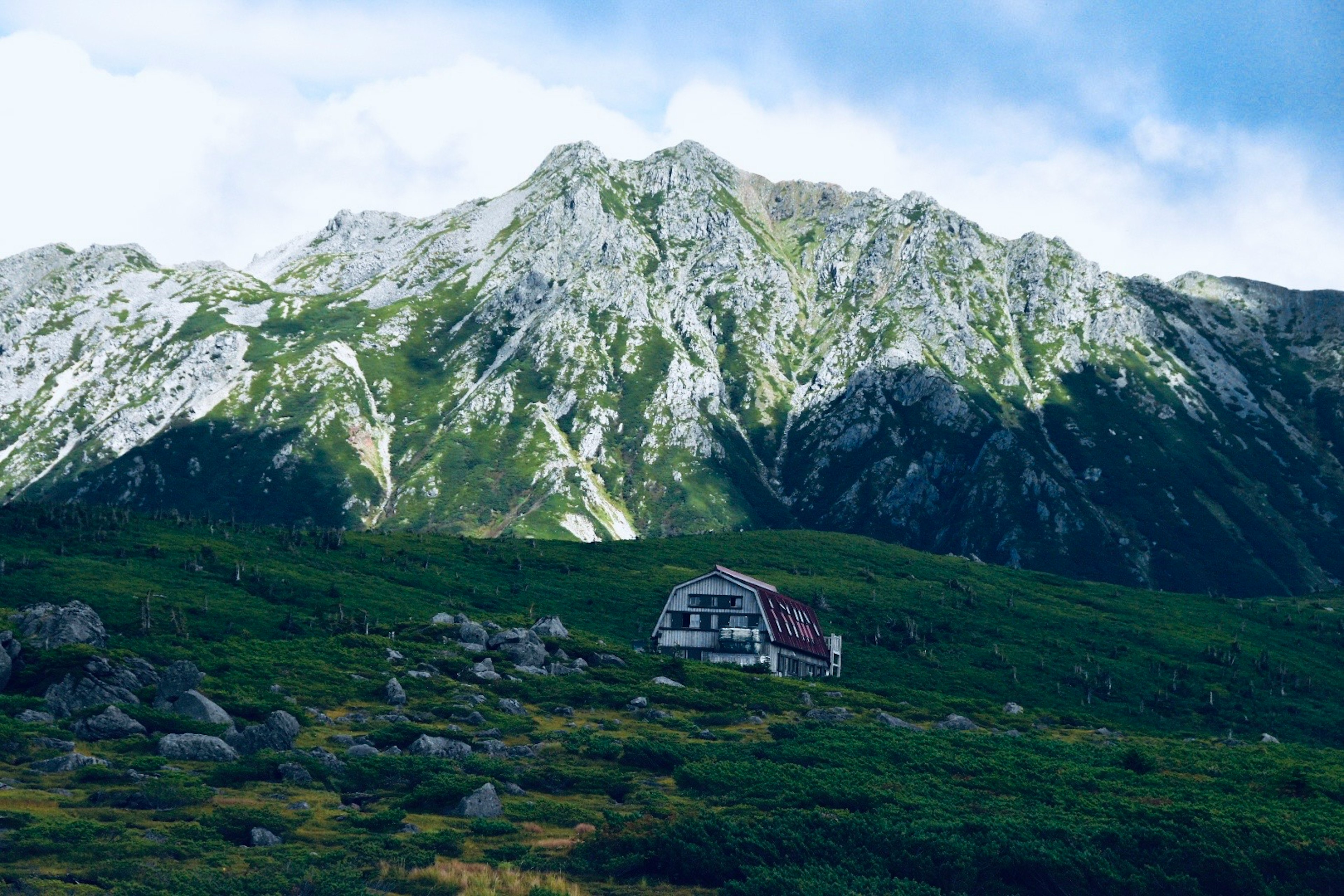 山の風景にある小さな建物と緑の草原