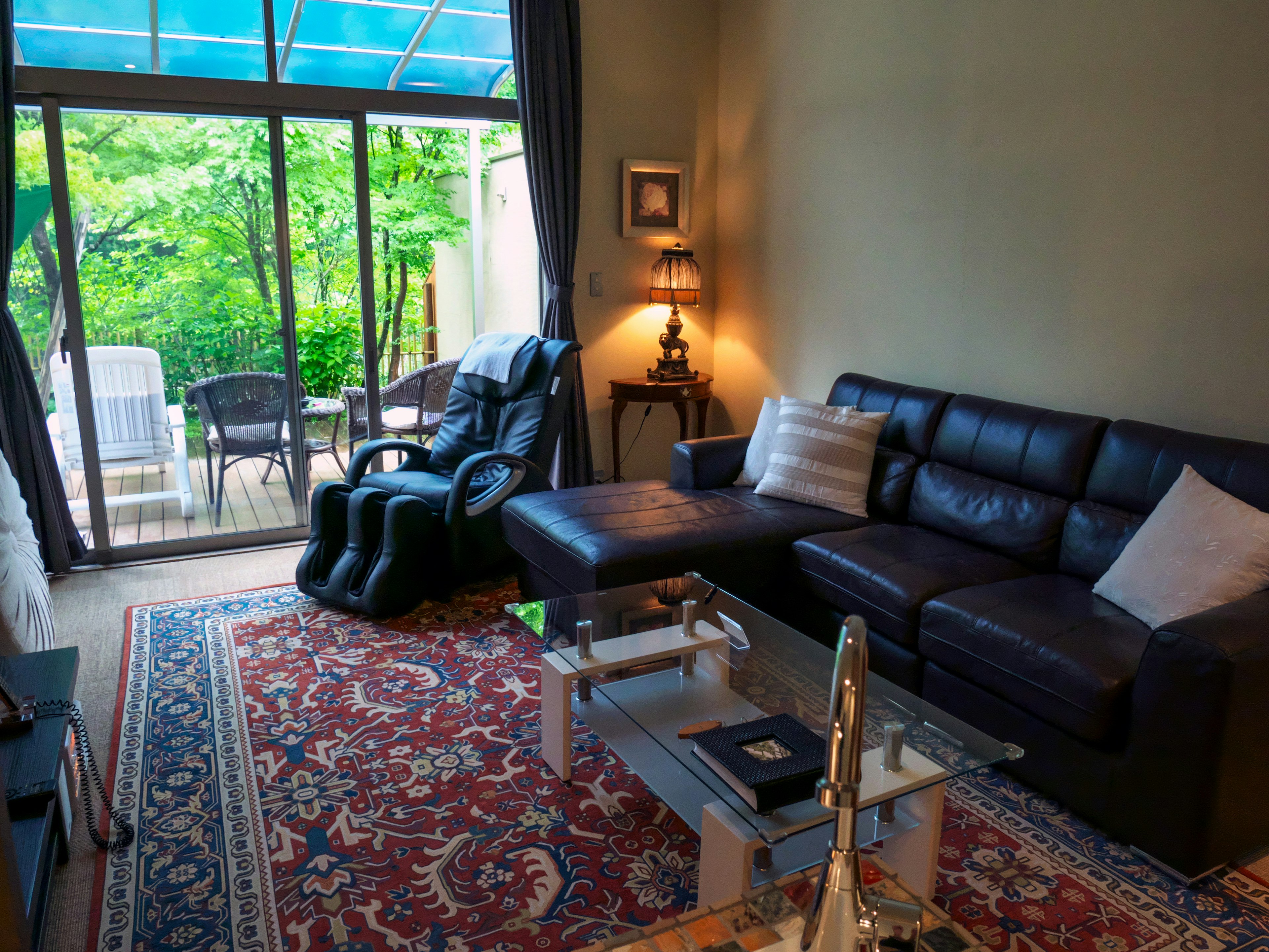 Living room with a view of greenery featuring a sofa and coffee table bright lighting and a patterned rug