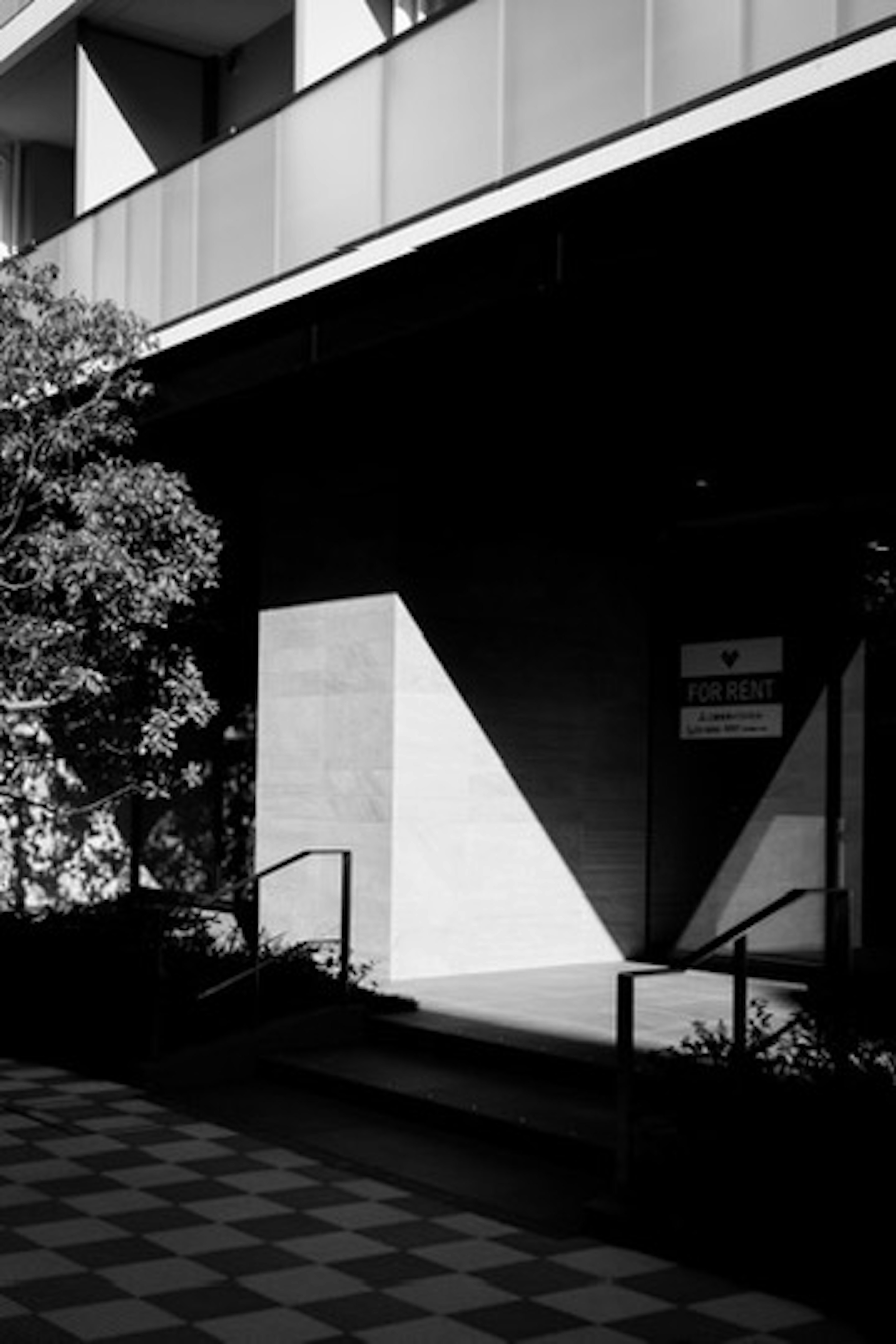 Contraste de lumière et d'ombre à l'entrée d'un bâtiment en noir et blanc