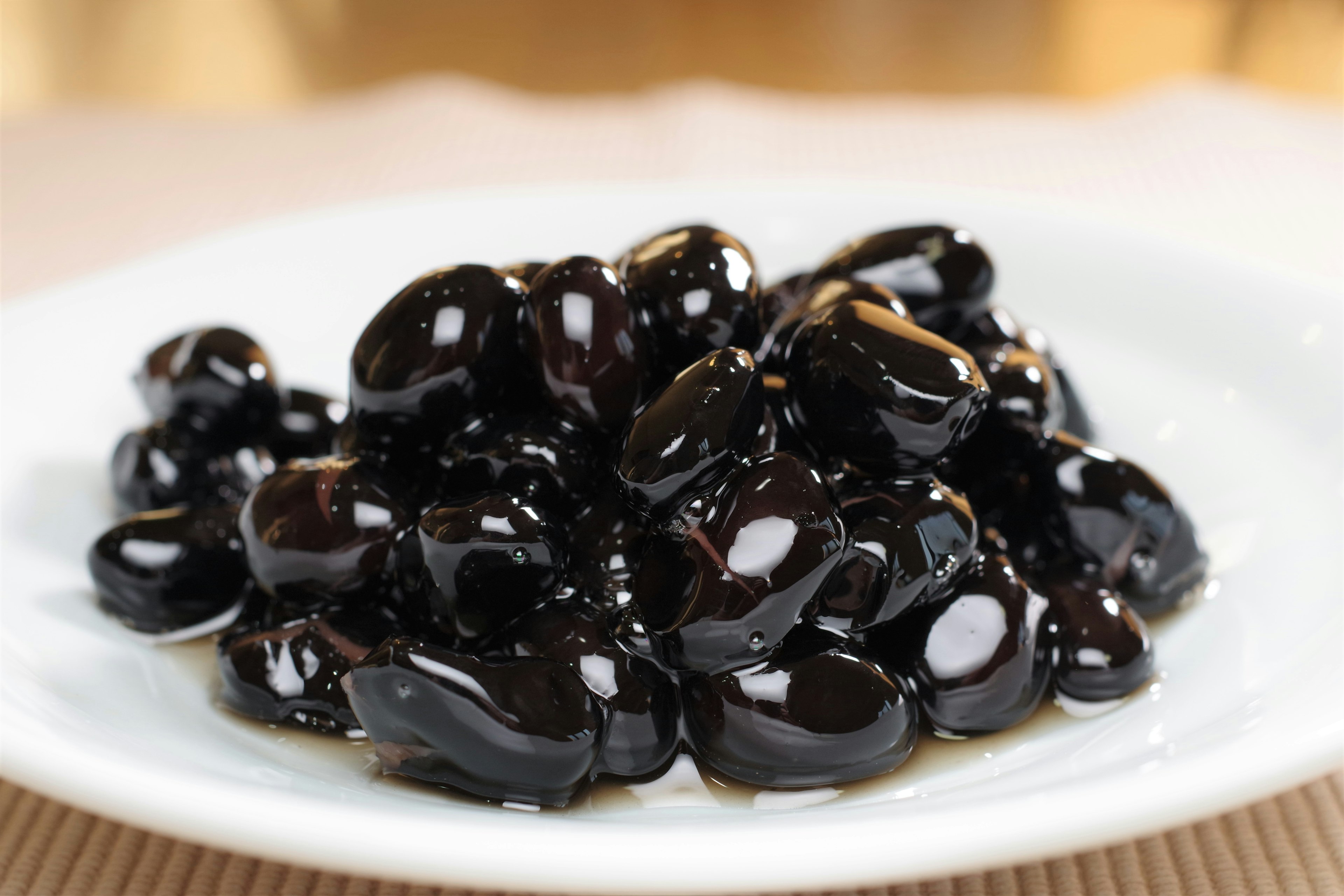 A mound of glossy black beans served on a white plate