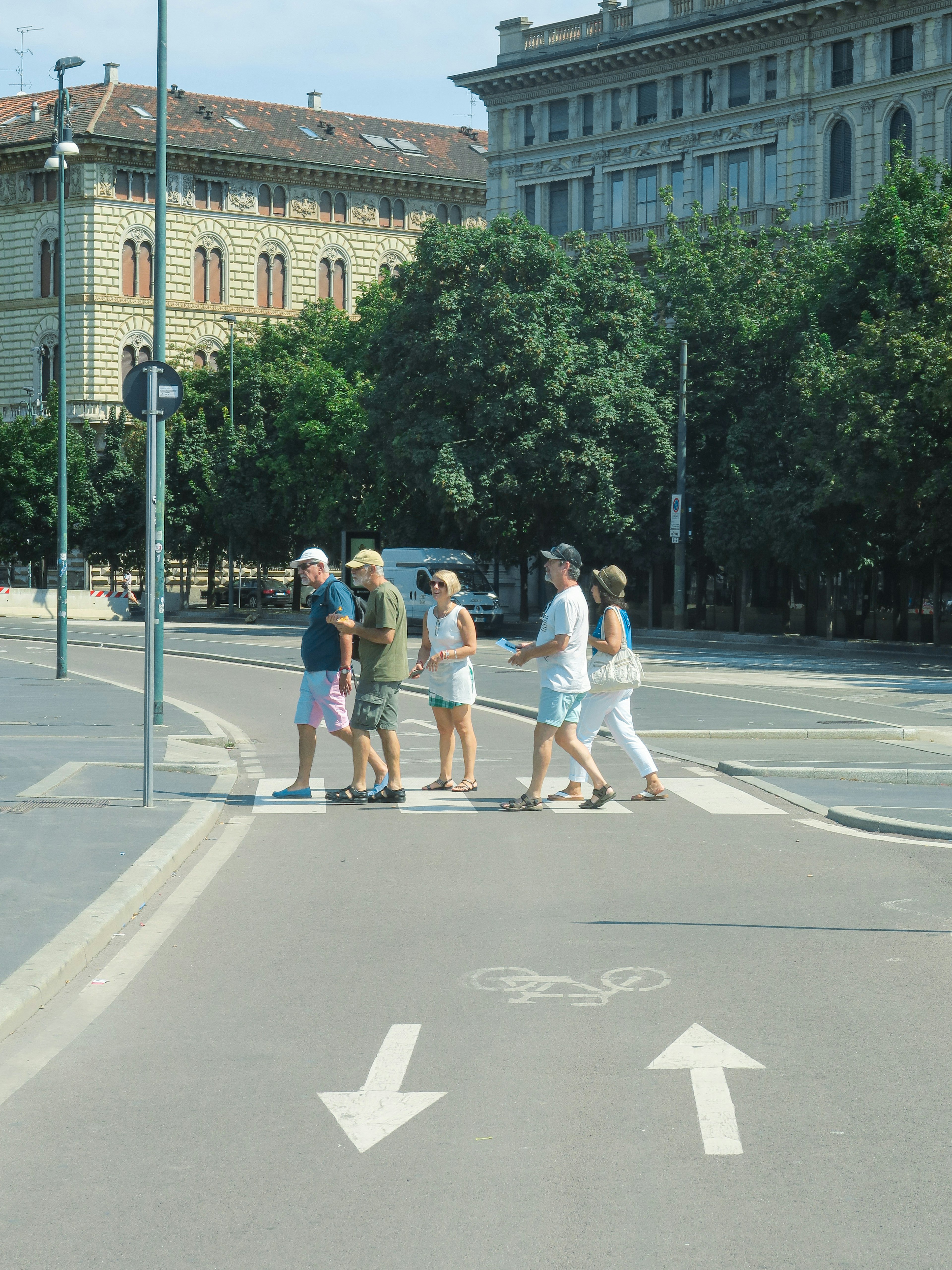 一群人正在街道上過馬路，背景是建築和樹木