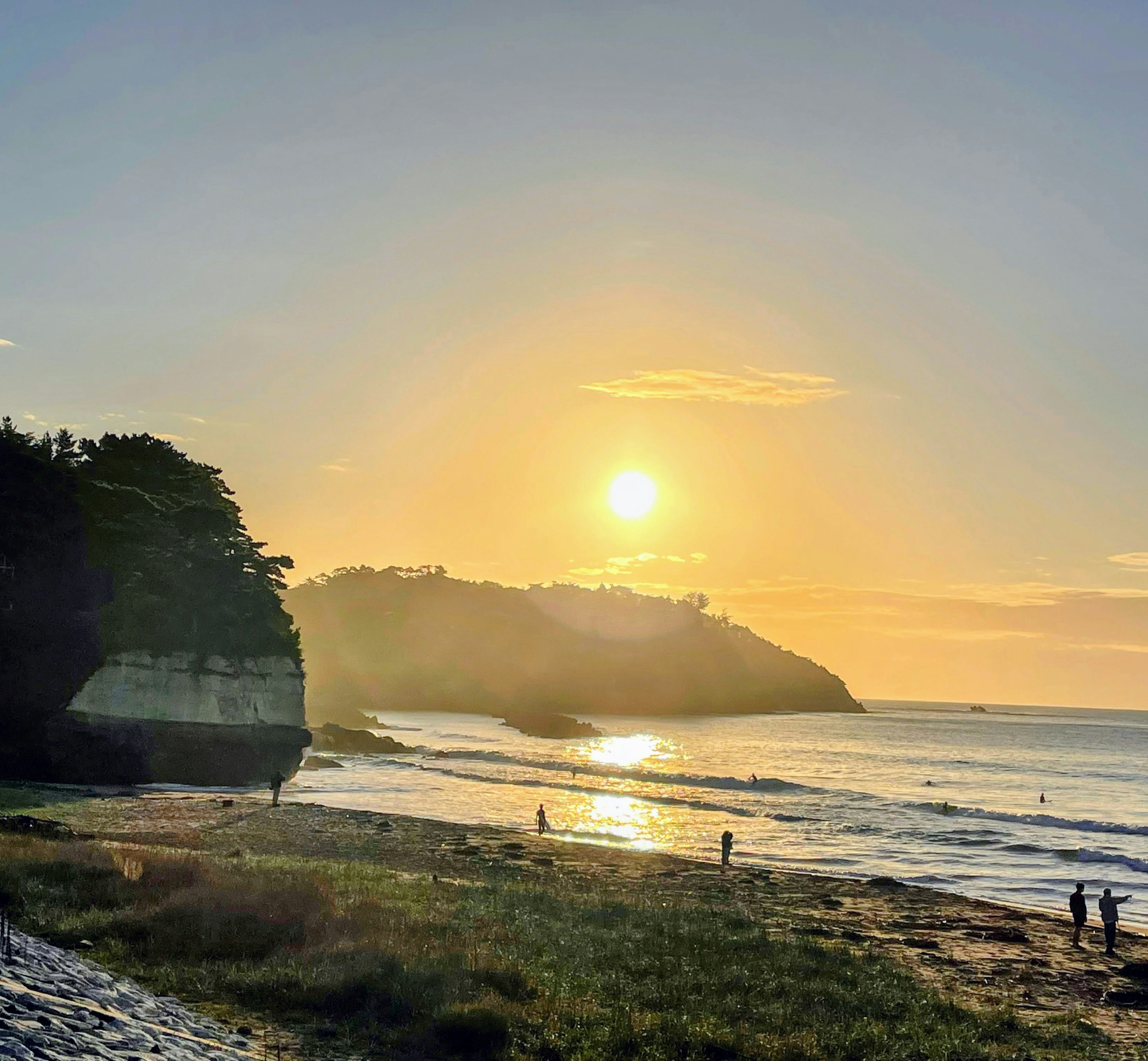 Beautiful beach landscape with sunset over the ocean people walking