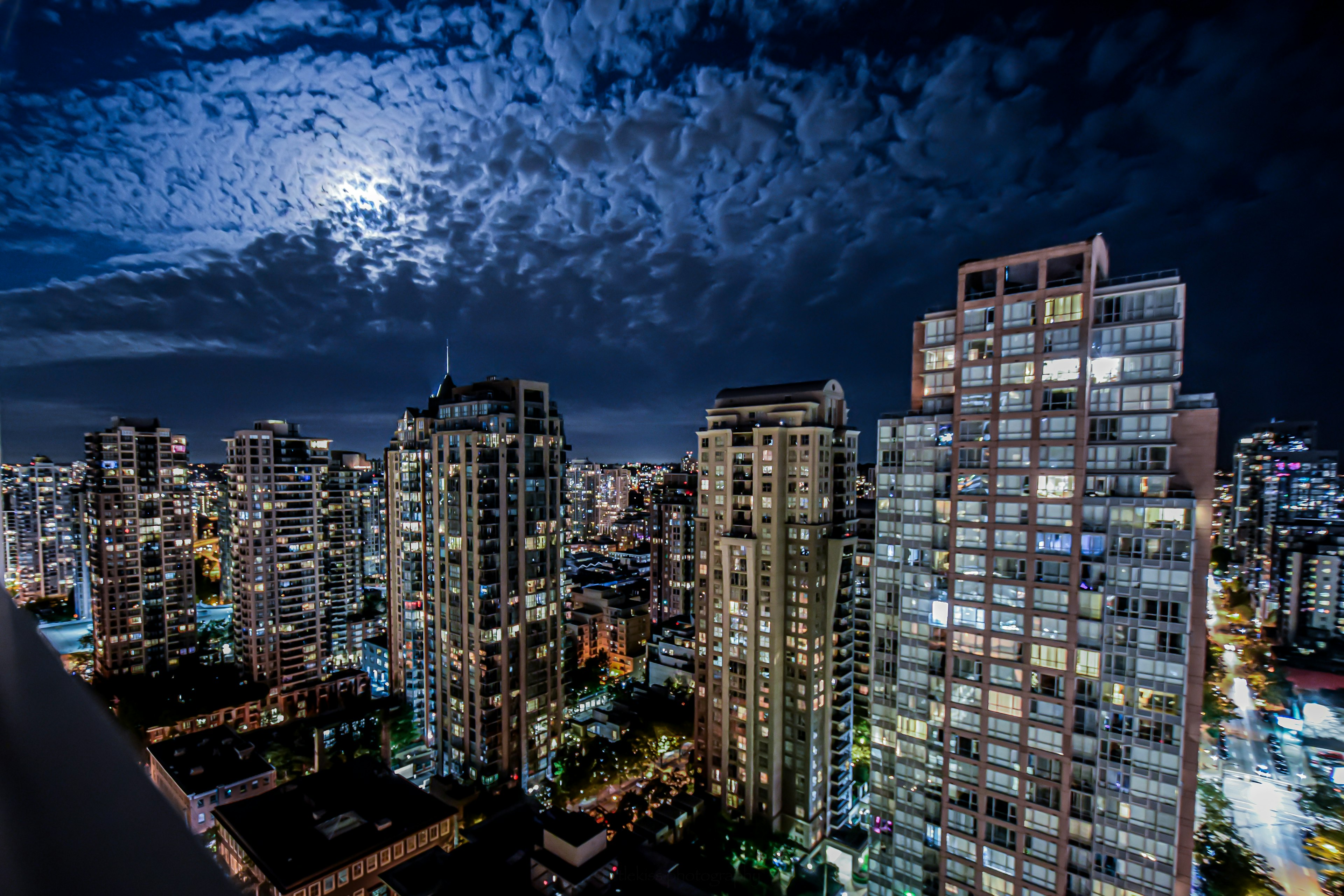 Horizonte de la ciudad de noche con luna brillante y nubes texturizadas