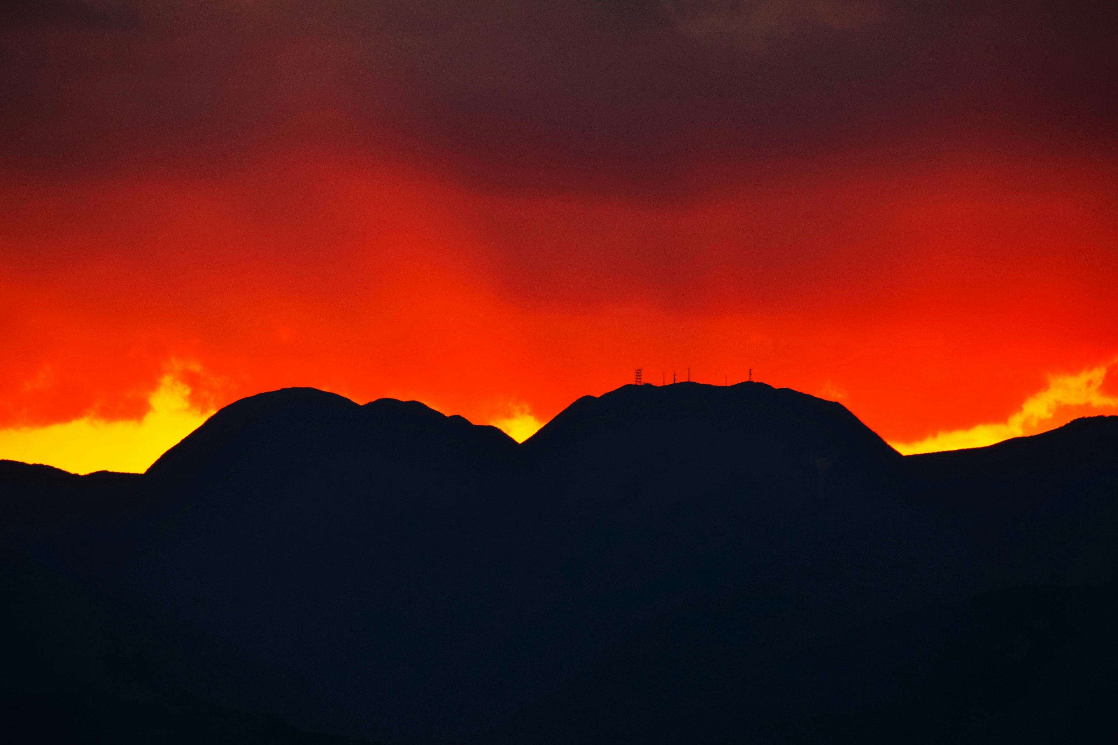 Silhouetted mountains against a vibrant red sunset sky