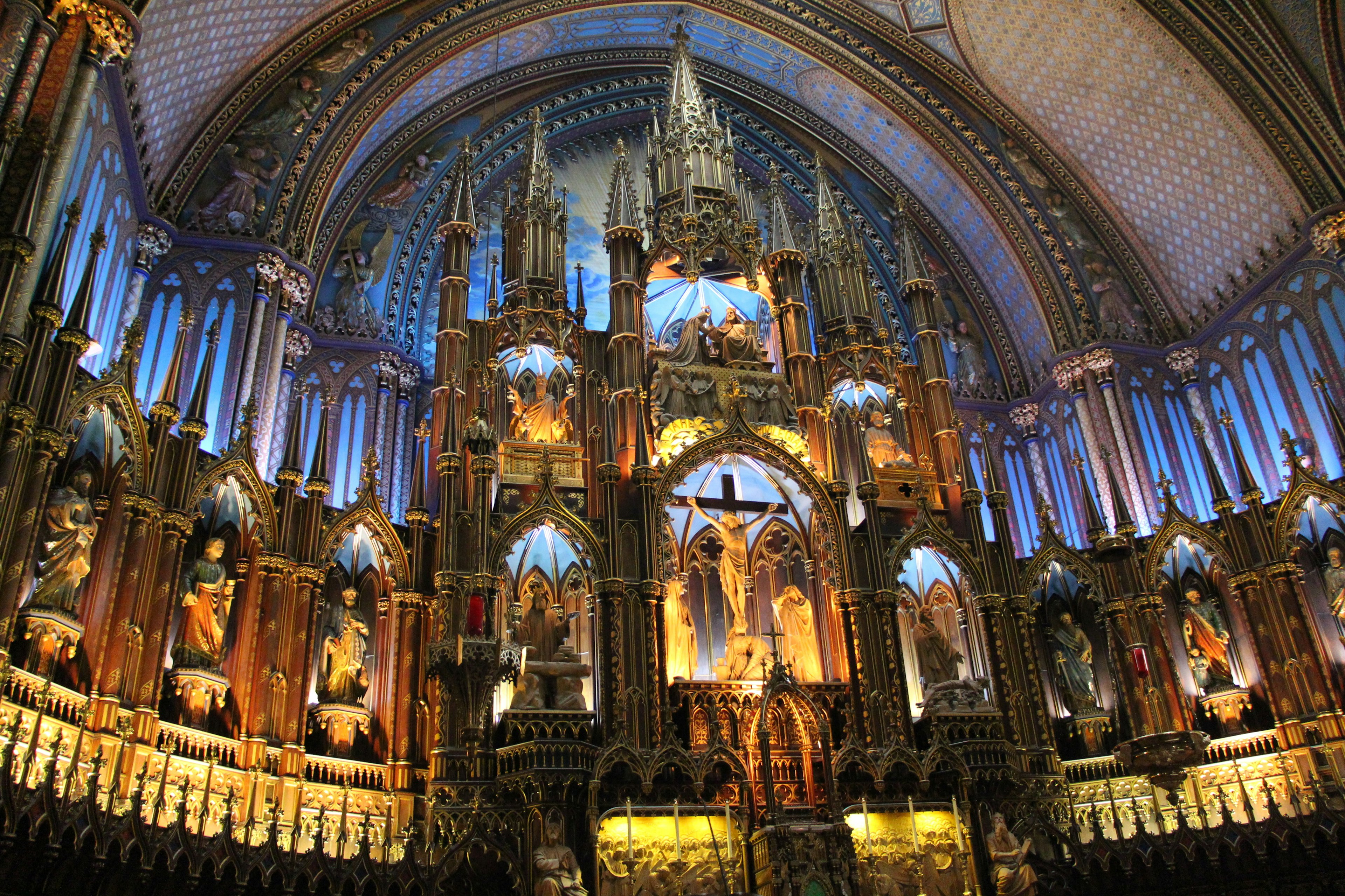 Interno della basilica di Notre-Dame a Montreal con grandi sculture e illuminazione blu sull'altare