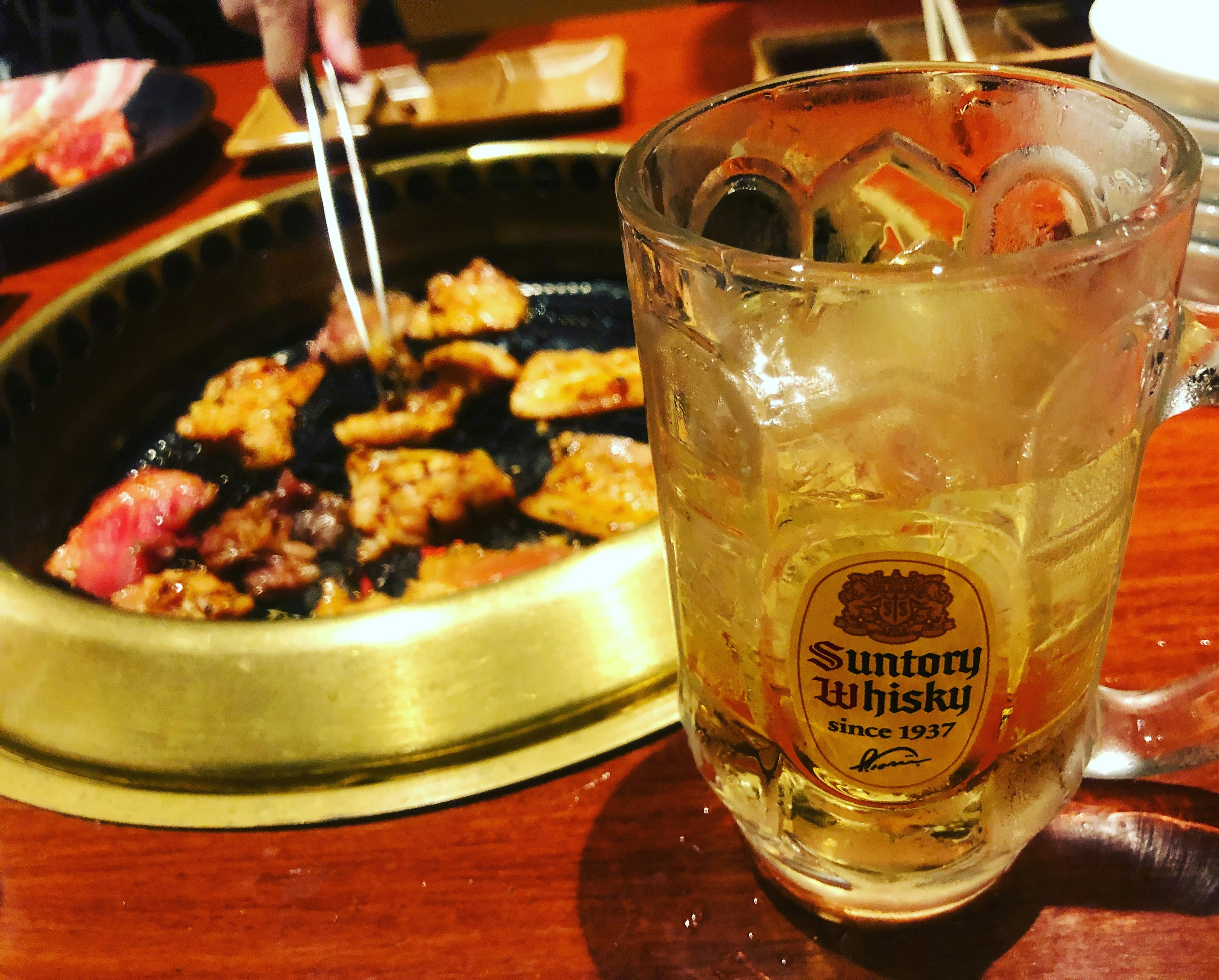 Scène de repas avec de la viande grillée et un verre de whisky Suntory