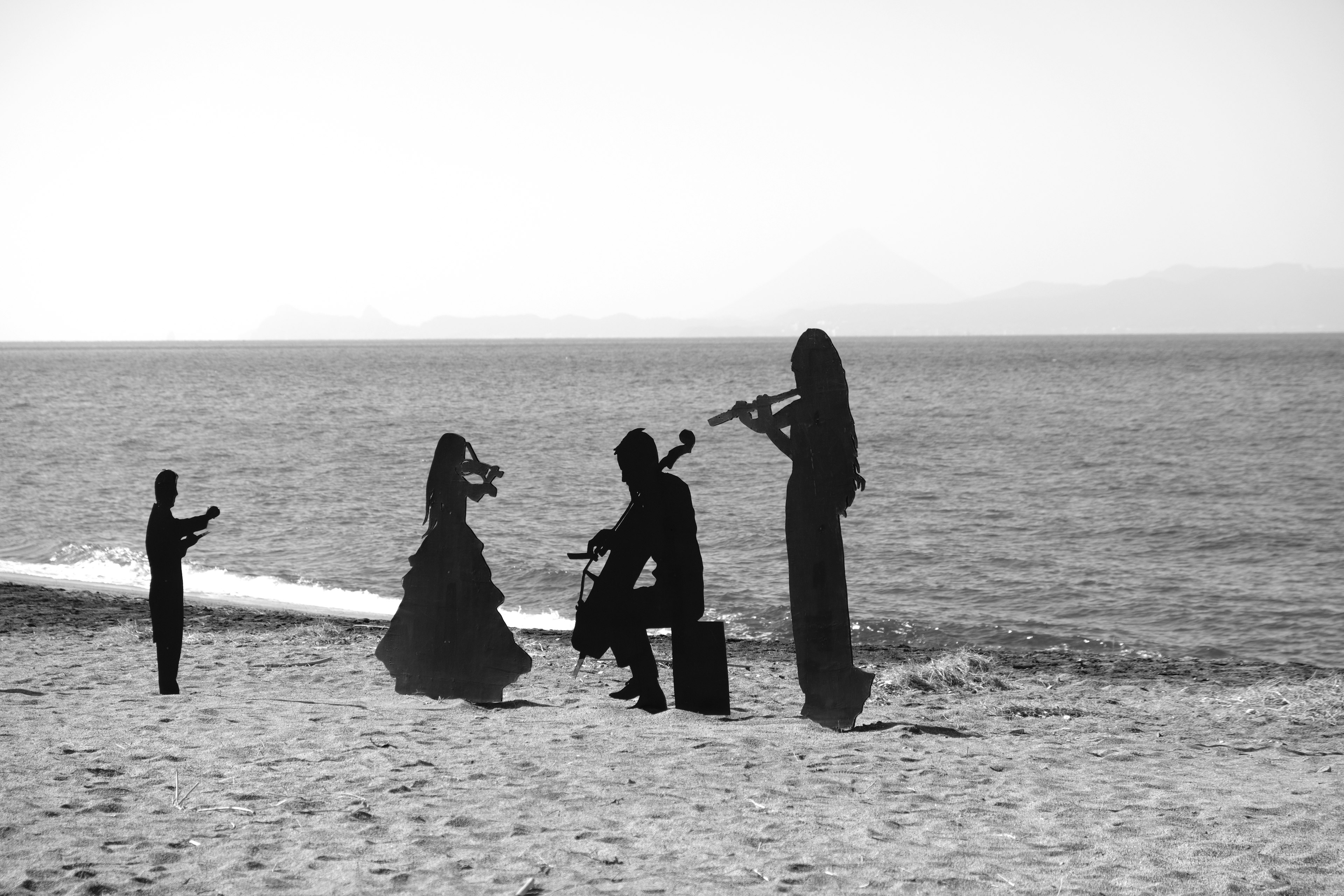 Silhouetten von Menschen, die am Strand Instrumente spielen