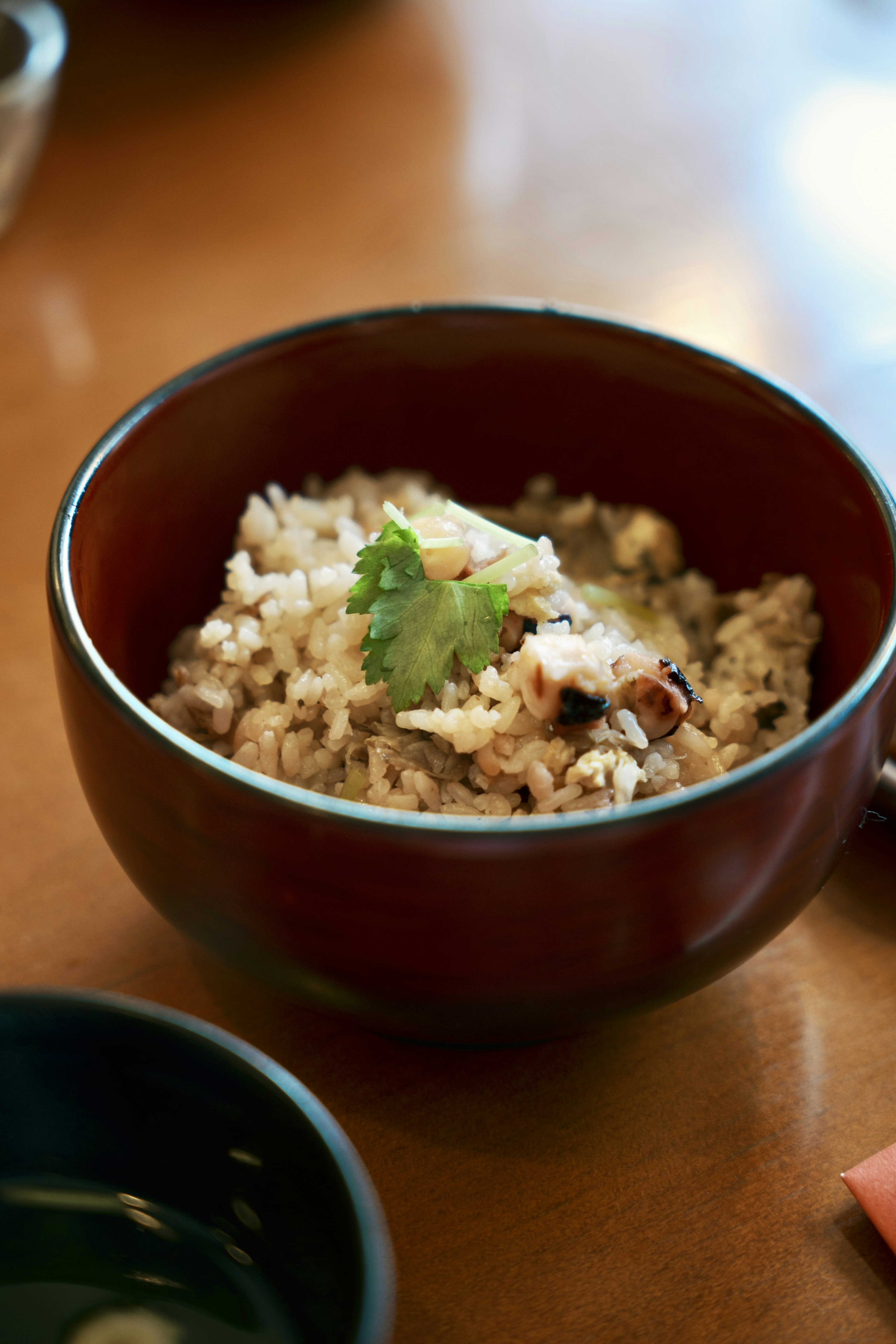 A bowl of risotto-style rice topped with herbs in a red bowl