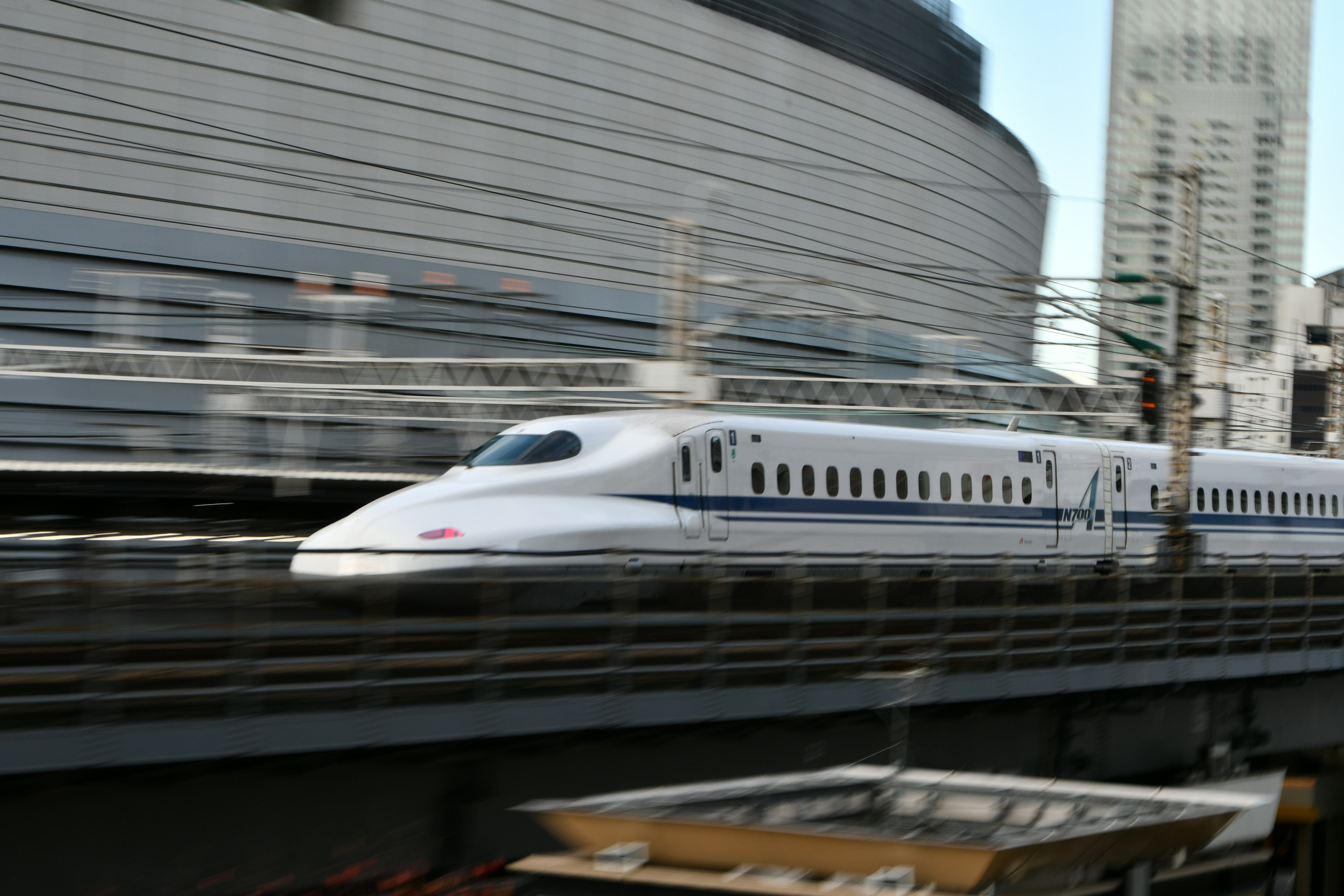 Shinkansen speeding by with city buildings in the background