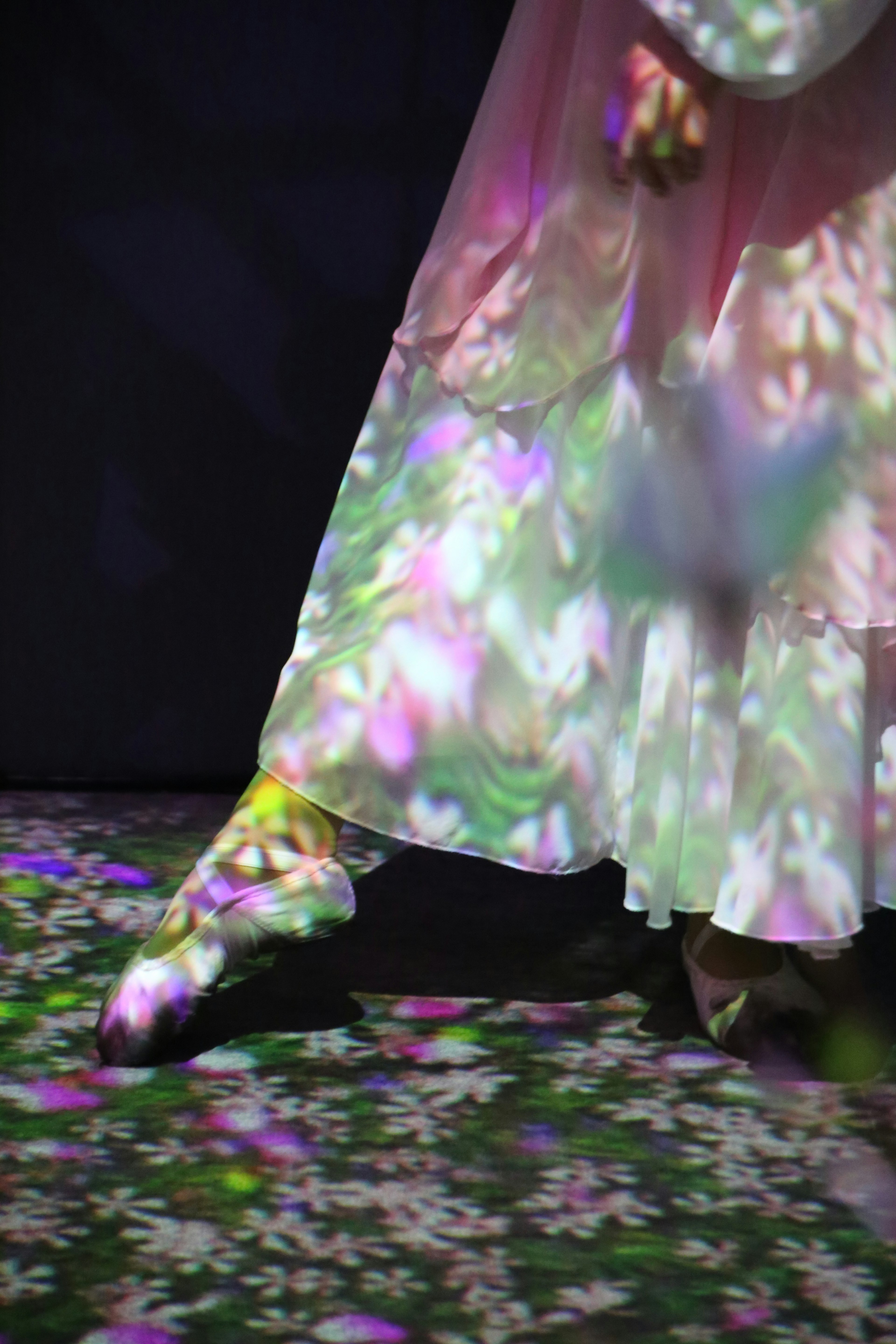 A woman's feet in a white dress with colorful floral projections