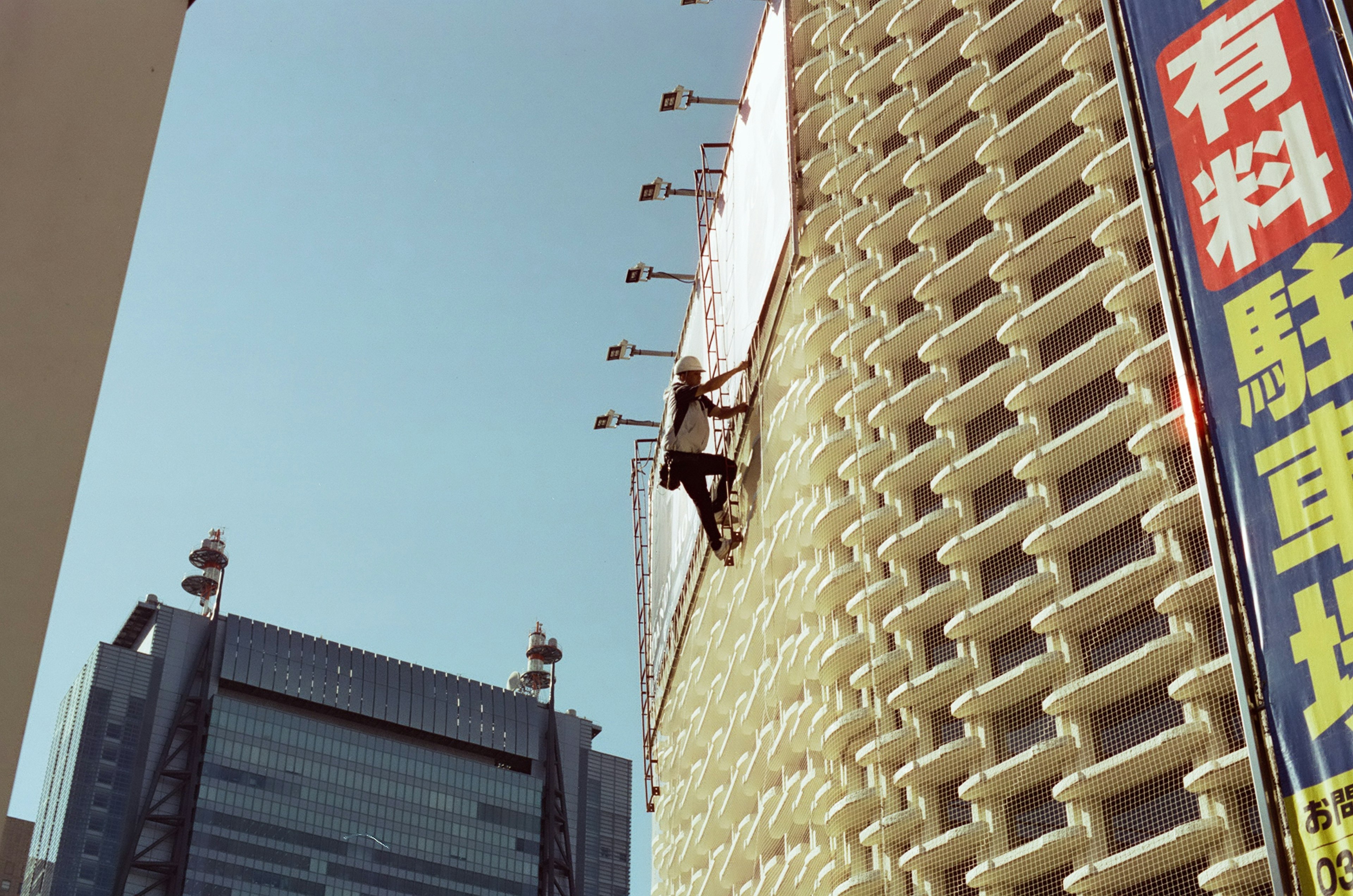 Travailleur grimpant sur la façade d'un bâtiment avec des gratte-ciel environnants