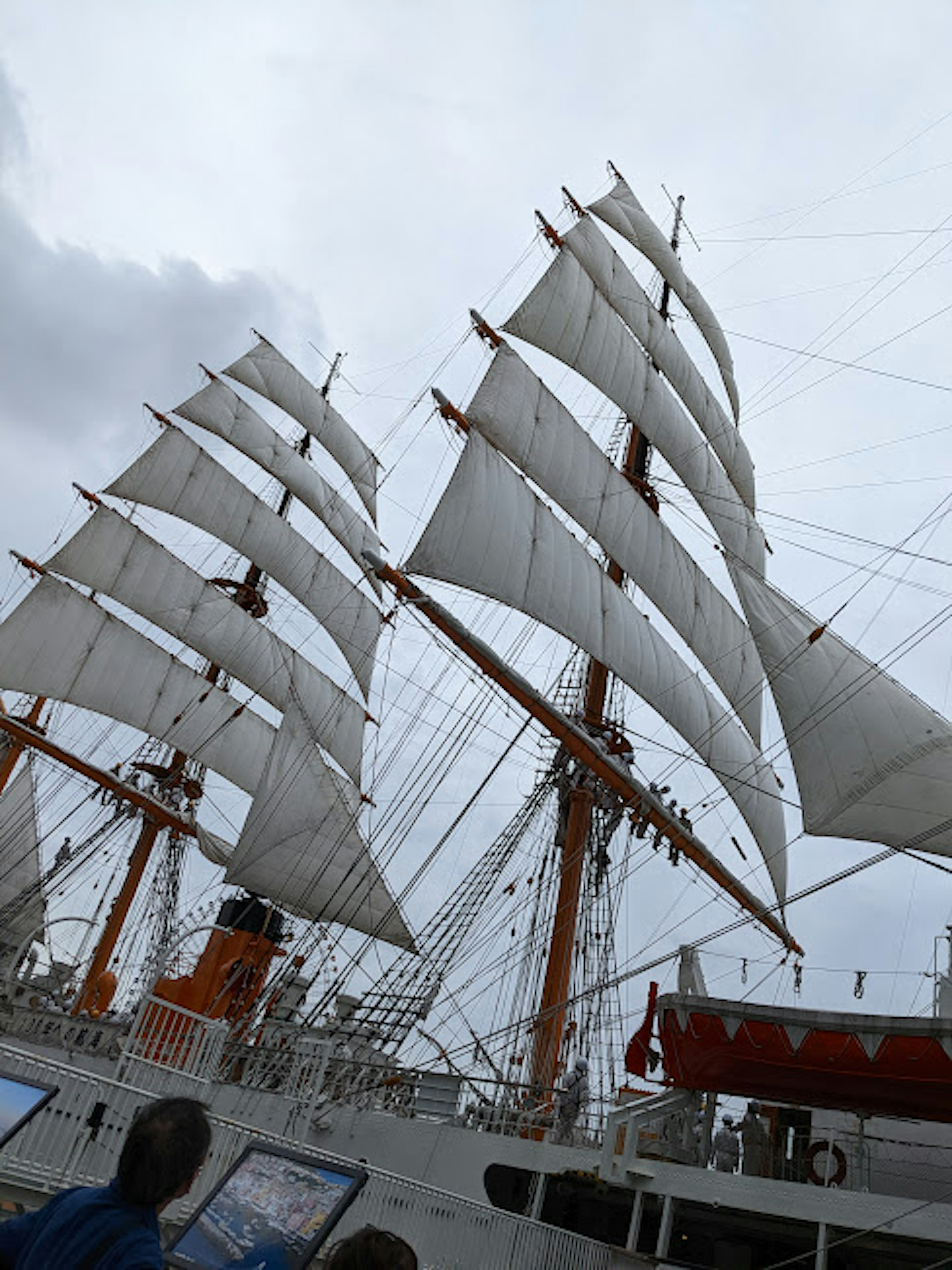 A large sailing ship with white sails and masts against a cloudy sky