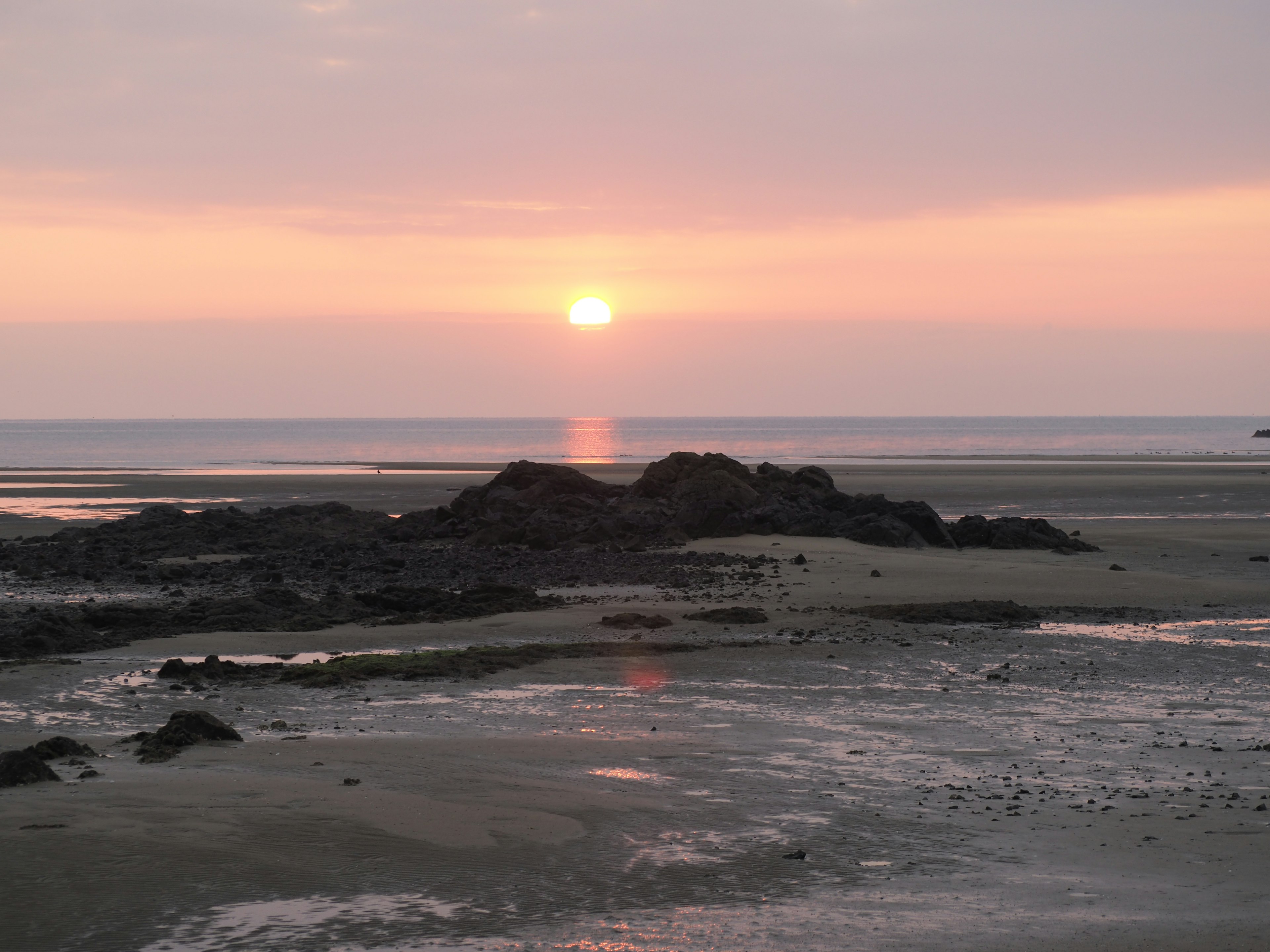 Coucher de soleil sur l'océan avec des rochers et une plage de sable