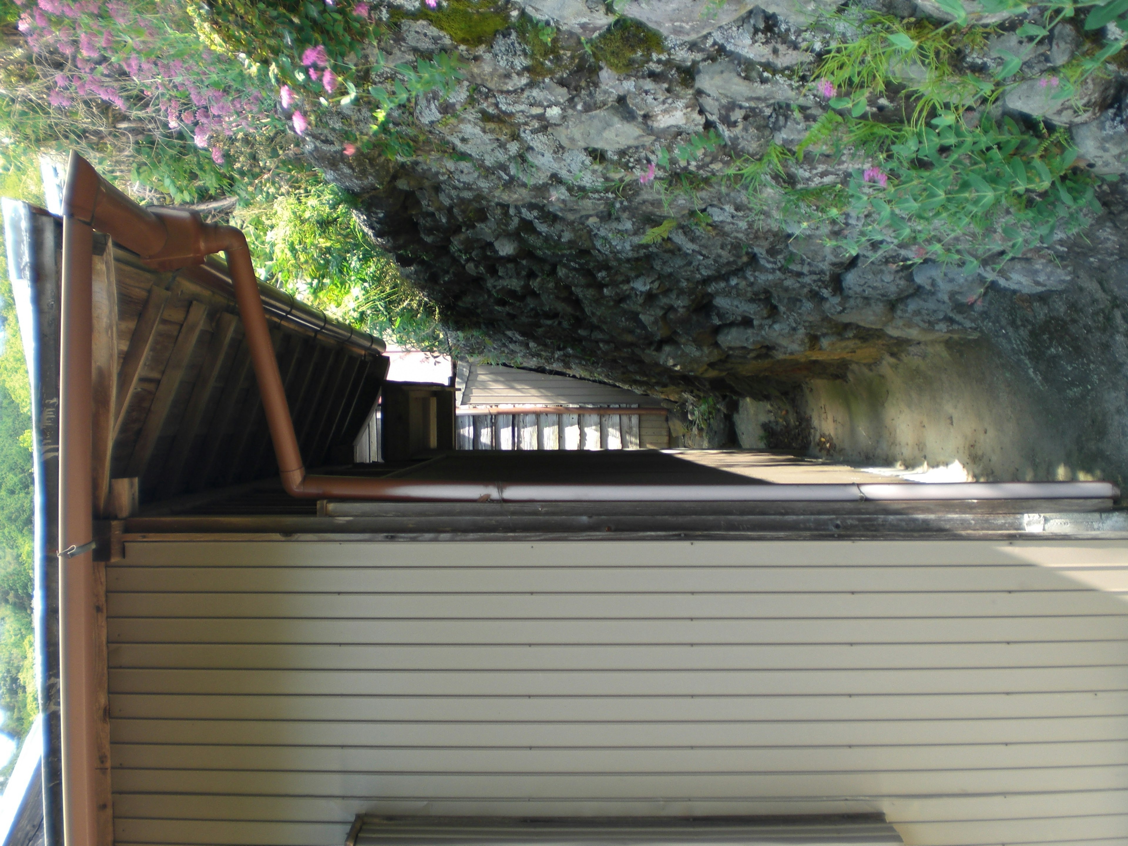 Traditional Japanese house exterior in front of a lush rocky wall