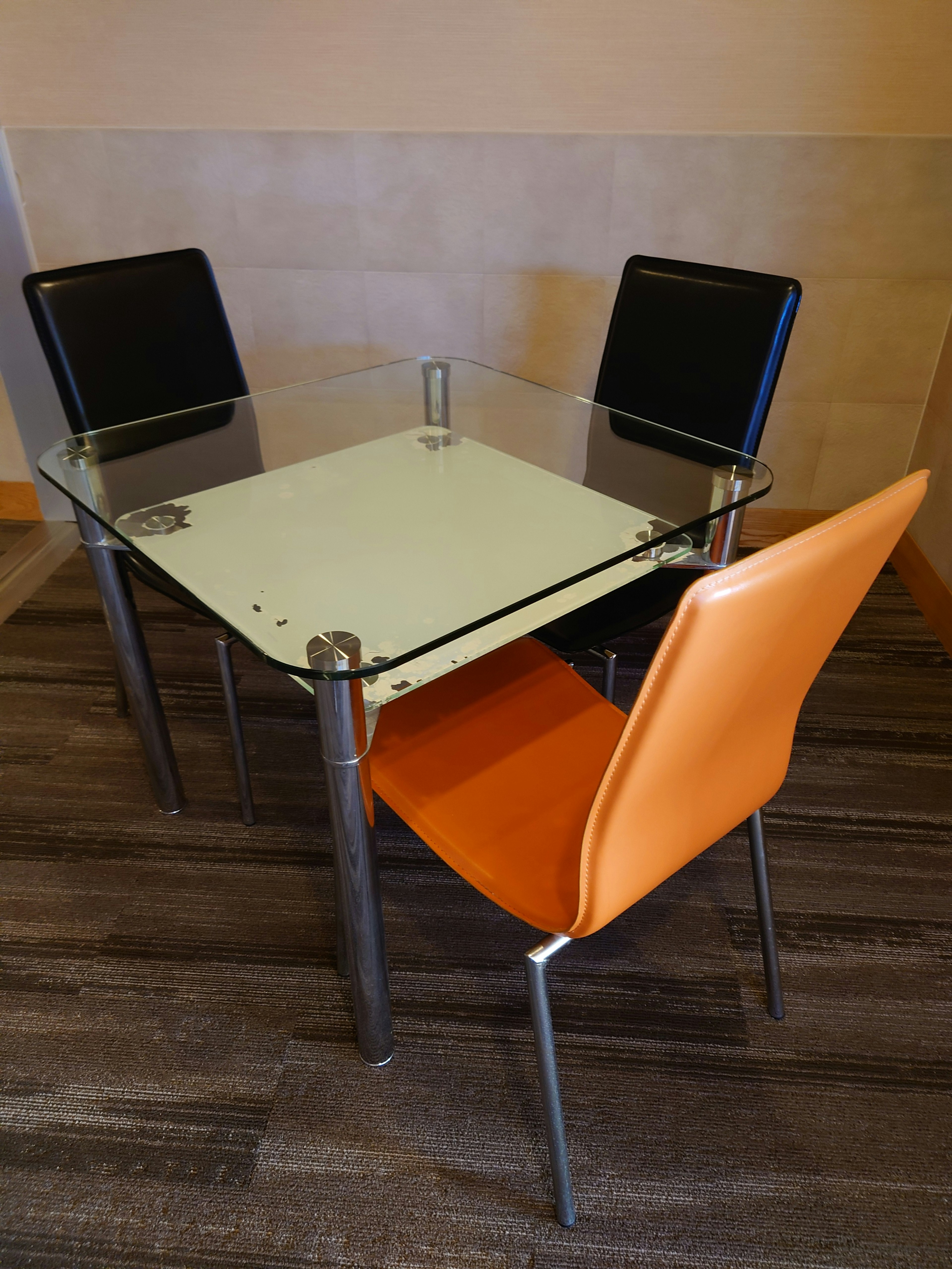 Modern dining set featuring a glass table and an orange chair