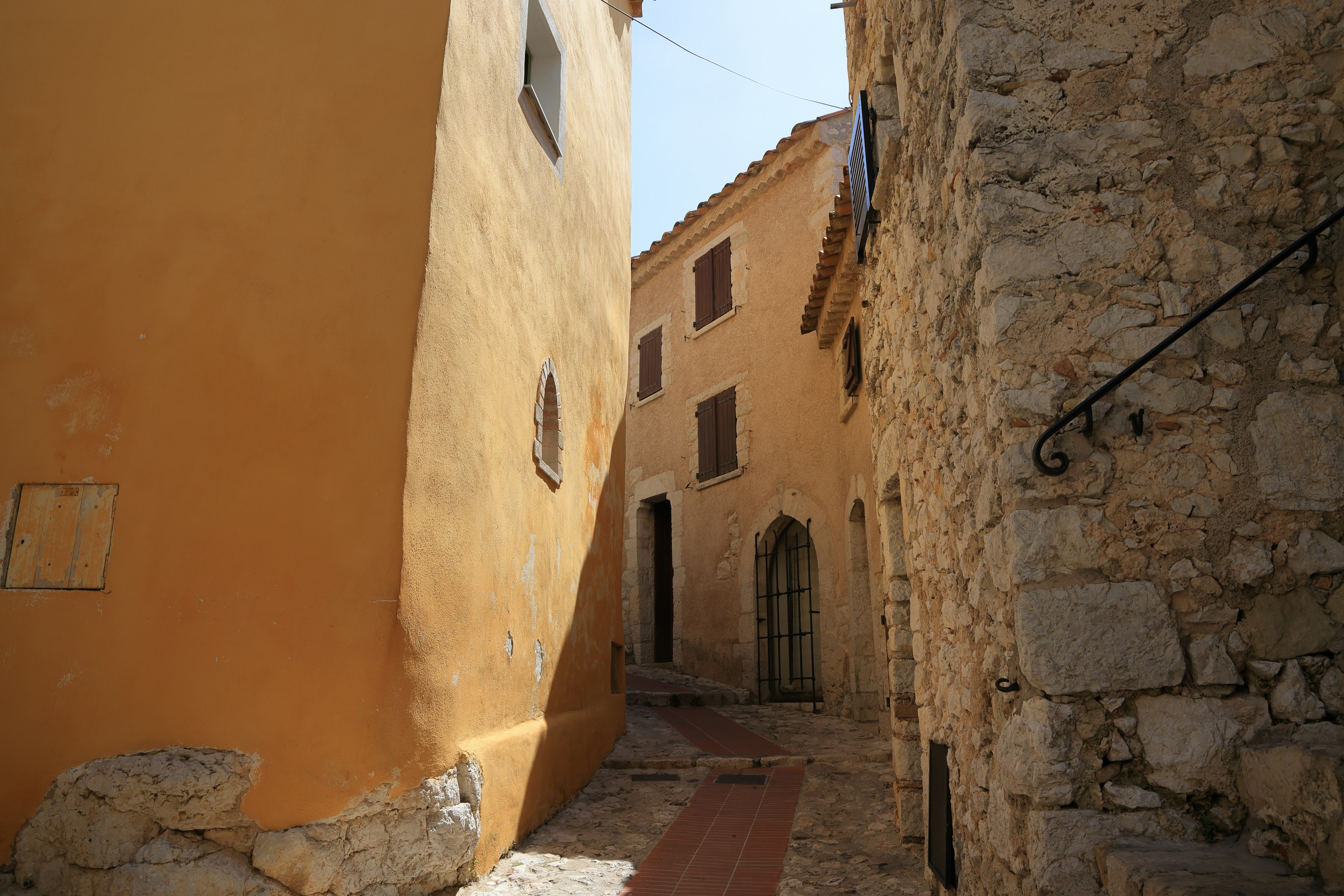 Narrow cobblestone alley with orange walls and stone buildings