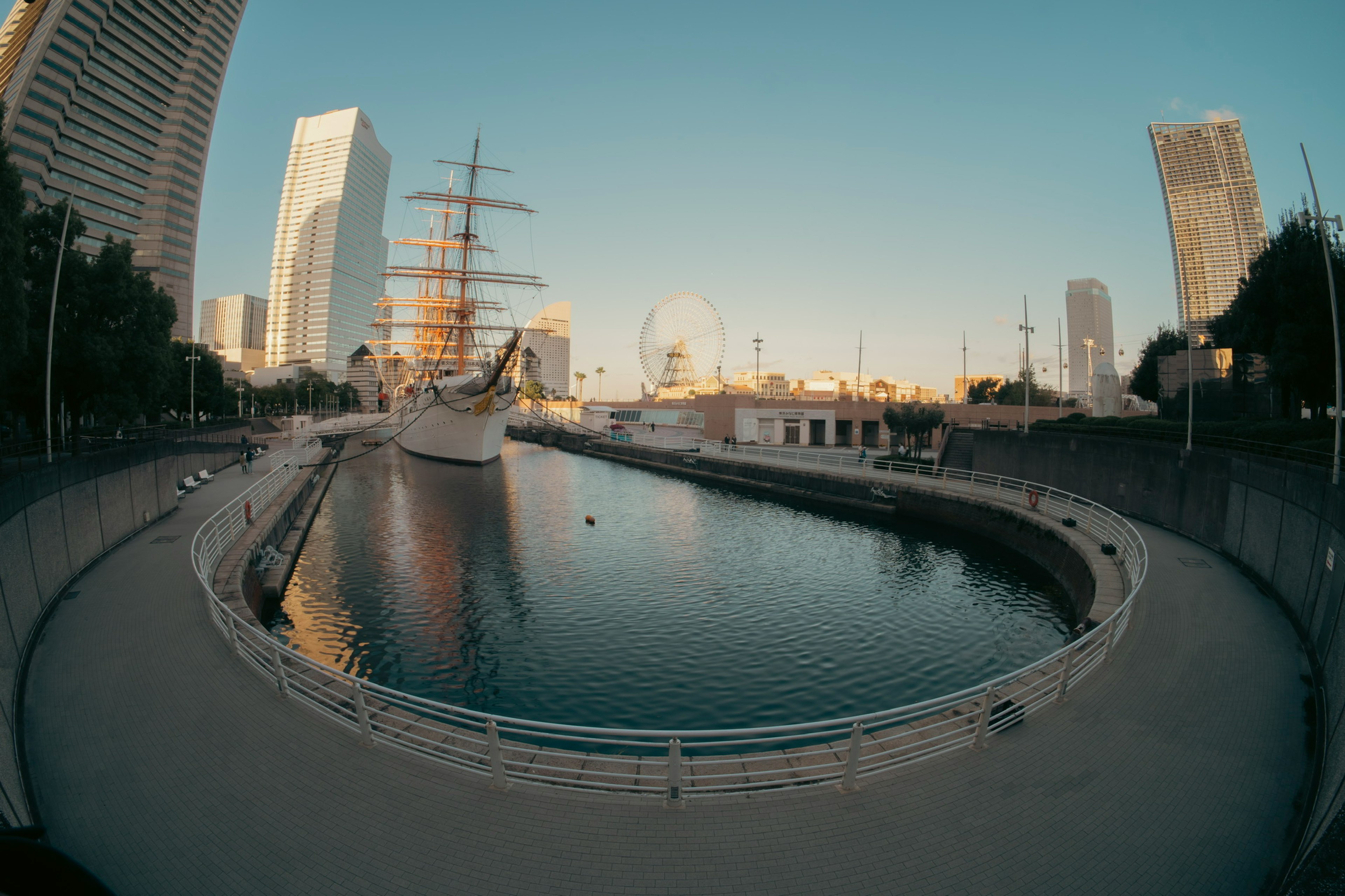 ทิวทัศน์ของเรือใบที่จอดอยู่ที่โยโกฮาม่าพร้อมตึกระฟ้าสมัยใหม่ในพื้นหลัง