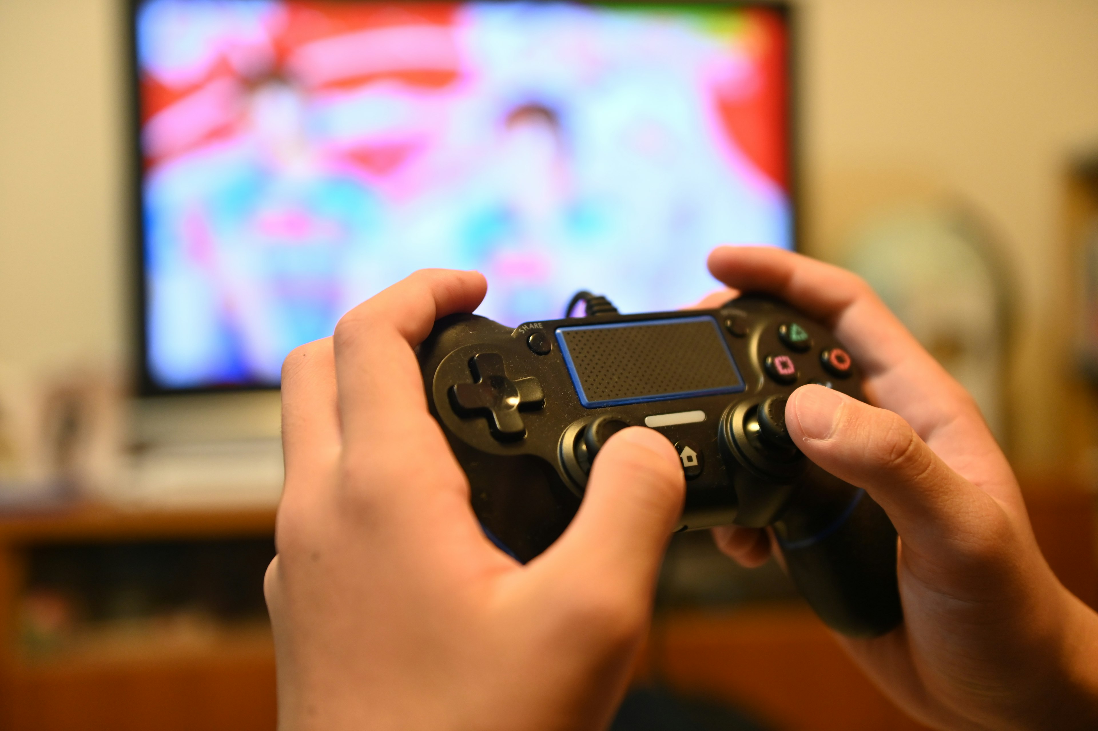 Hands holding a game controller with a television in the background