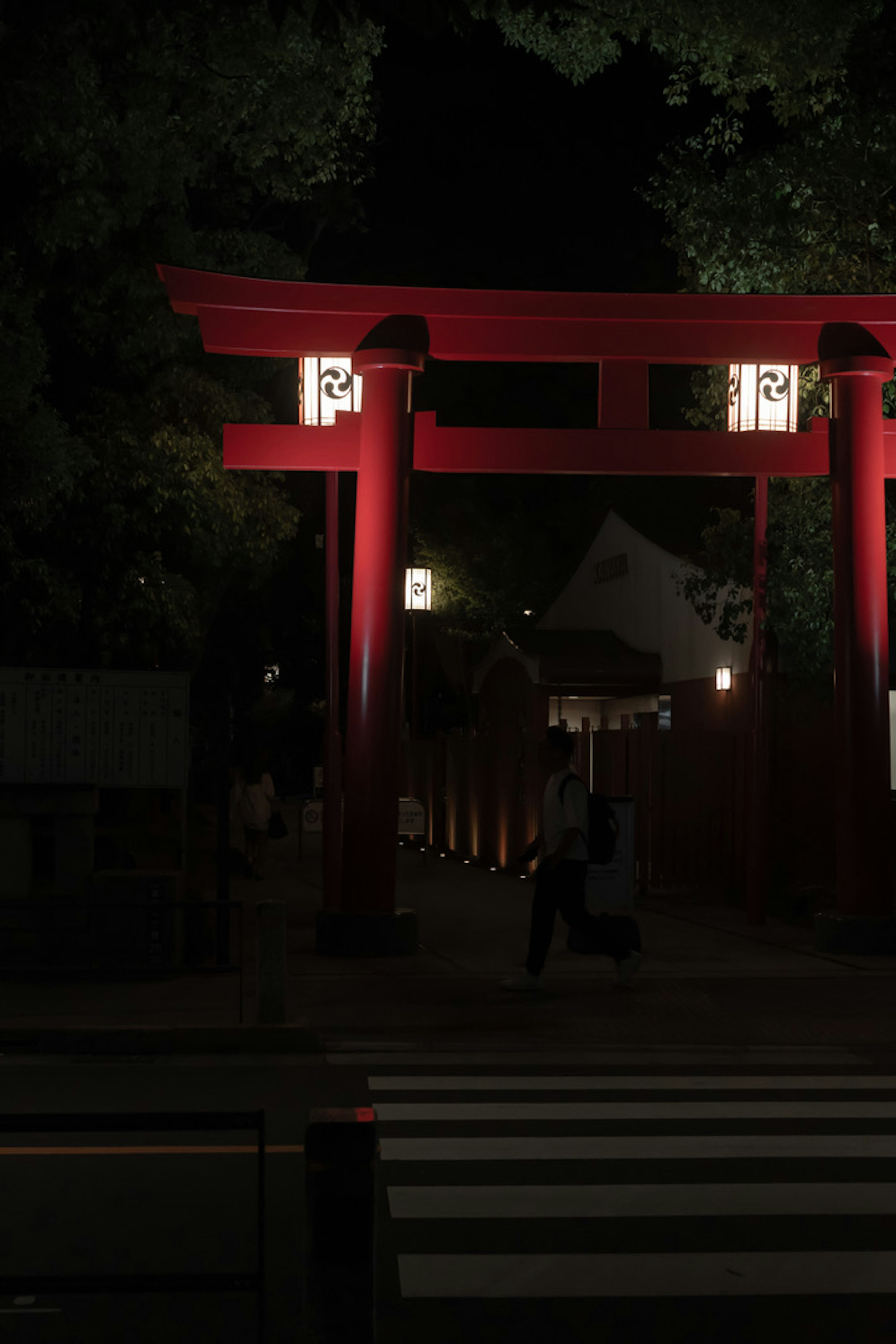 Vue nocturne d'un torii rouge éclairé par des lanternes