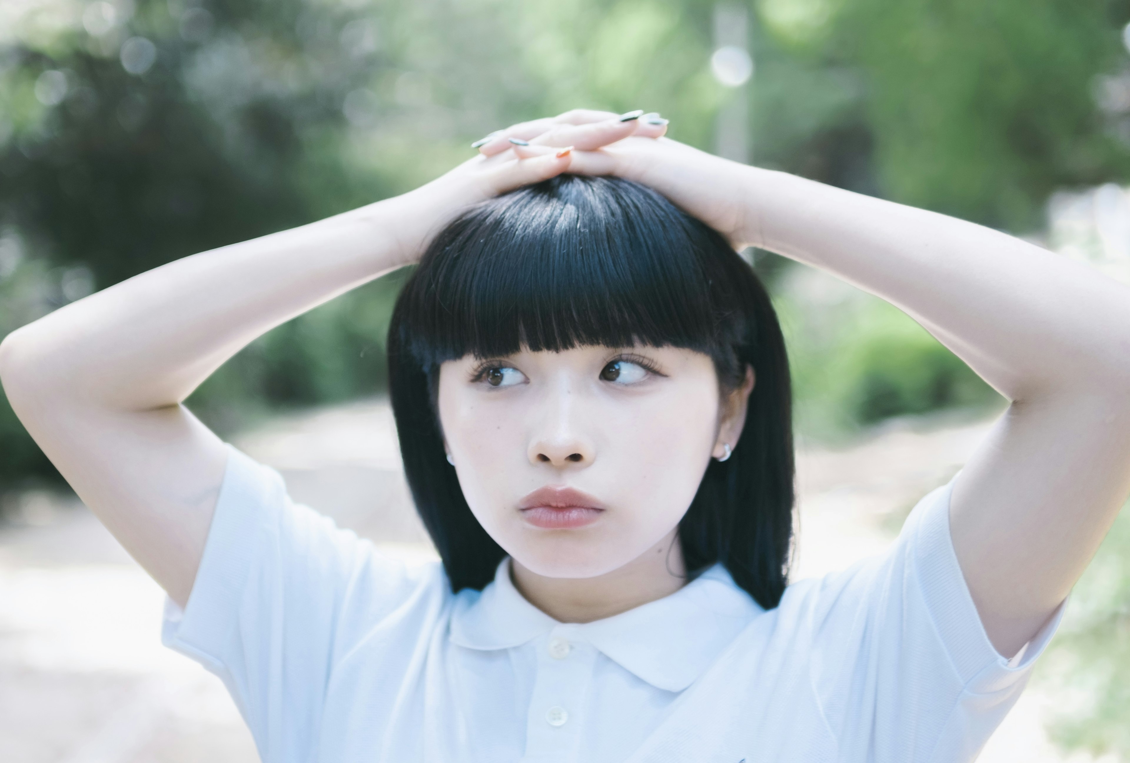 A woman in a white shirt holding her head with both hands looking contemplative