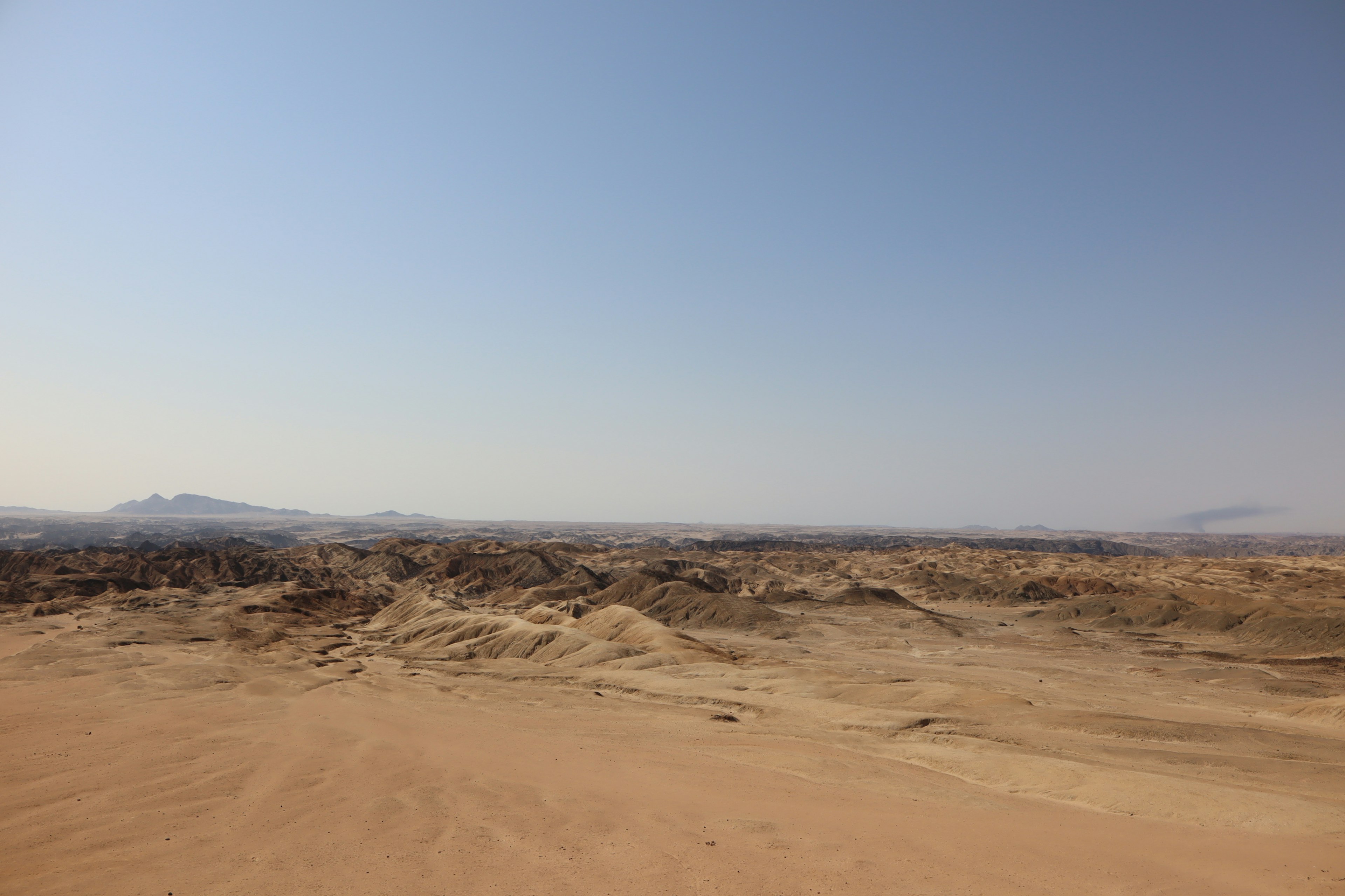 Vast desert landscape with blue sky and rolling sand dunes