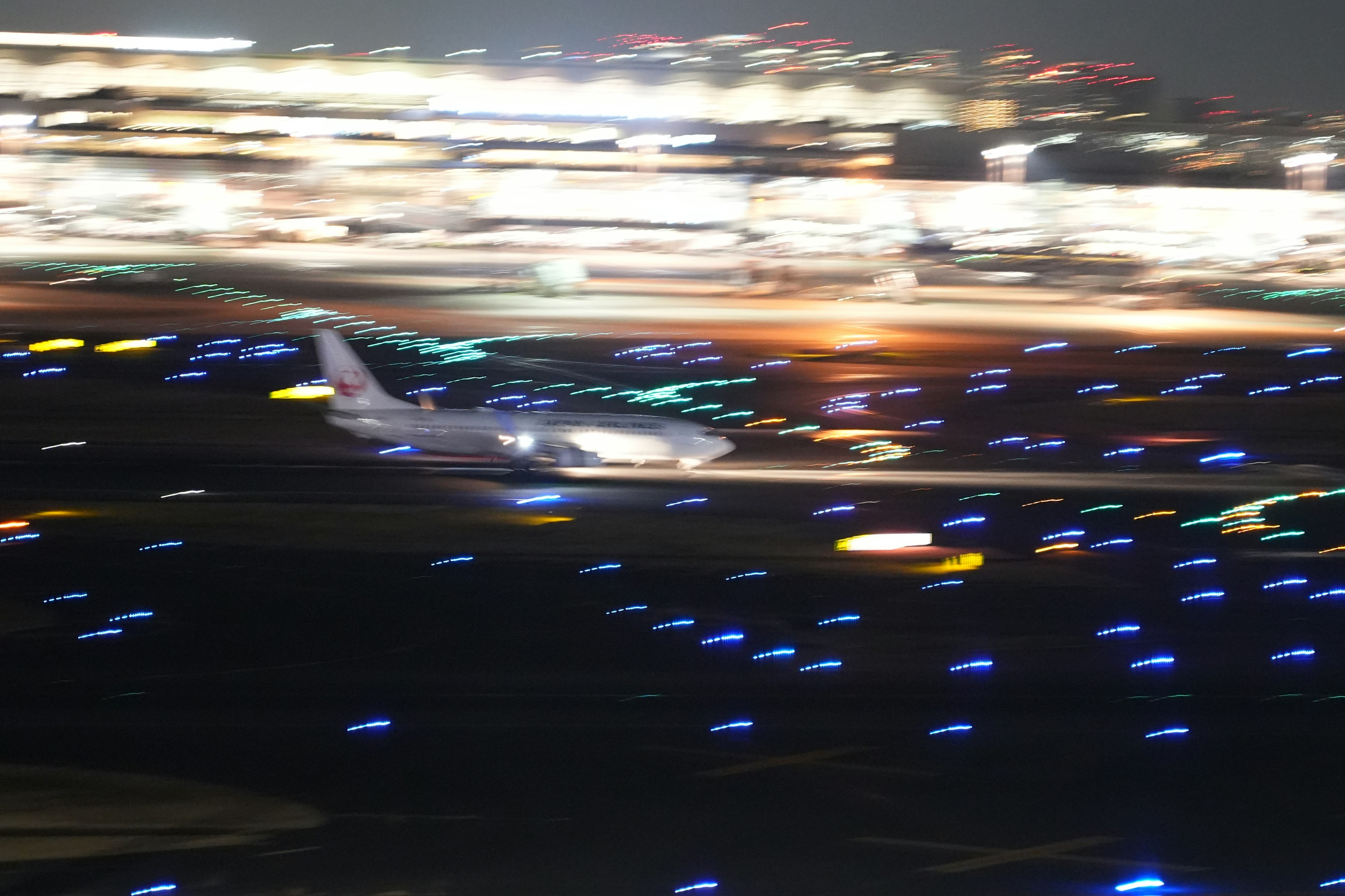 Airplane taking off at night with colorful runway lights