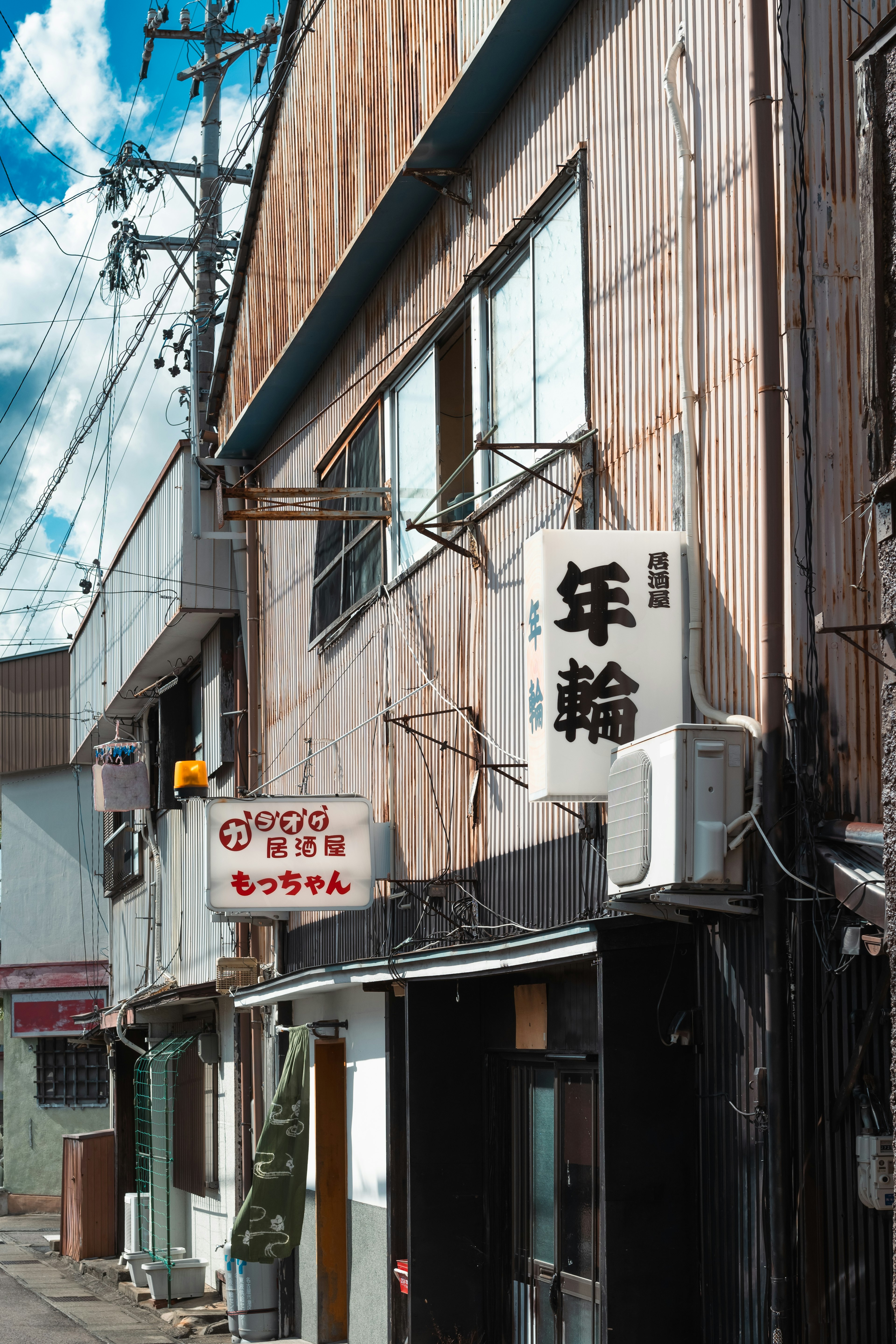 Straßenansicht mit einem alten Holzgebäude und japanischen Schildern