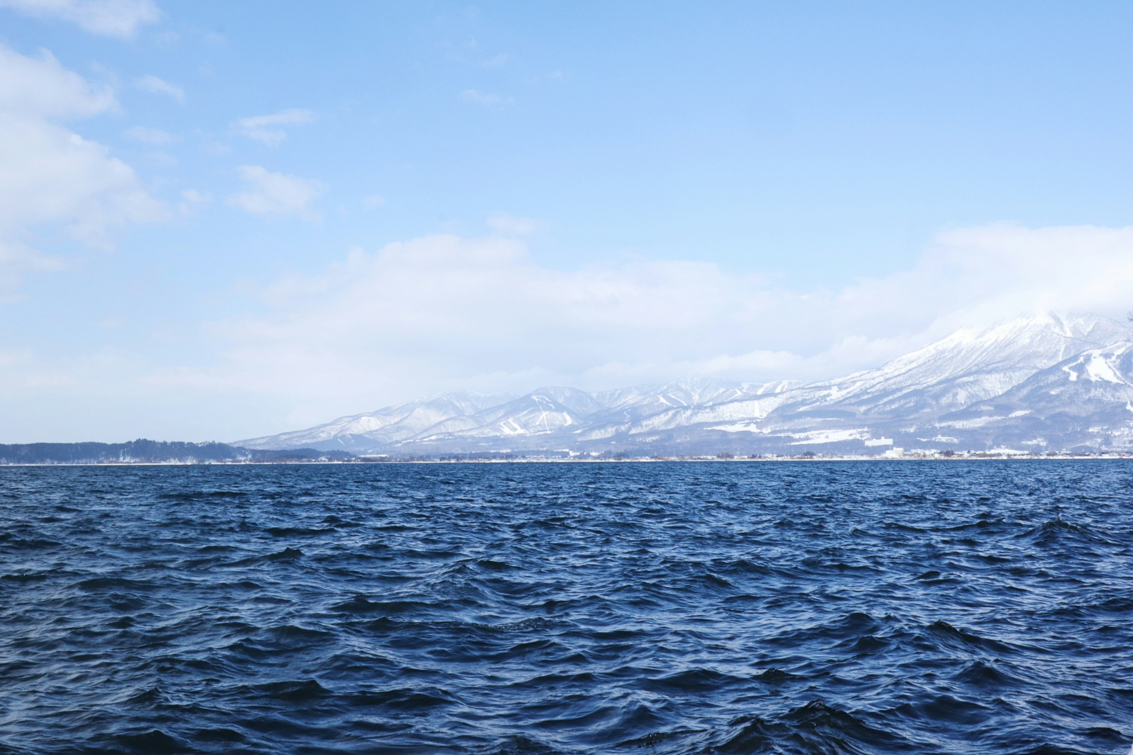 Un paesaggio con un mare blu e montagne innevate