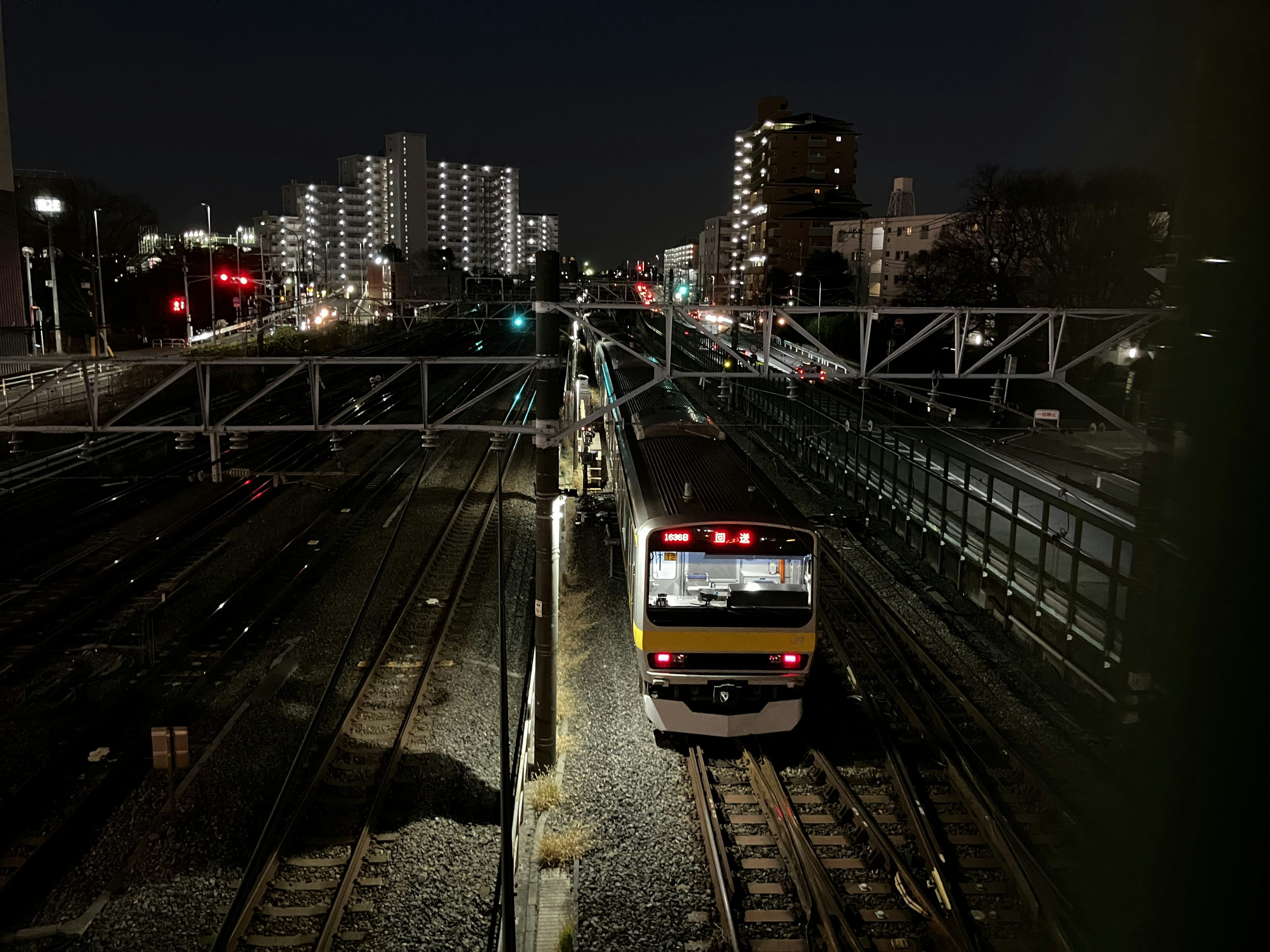 Tren detenido en una estación de tren de noche con edificios circundantes