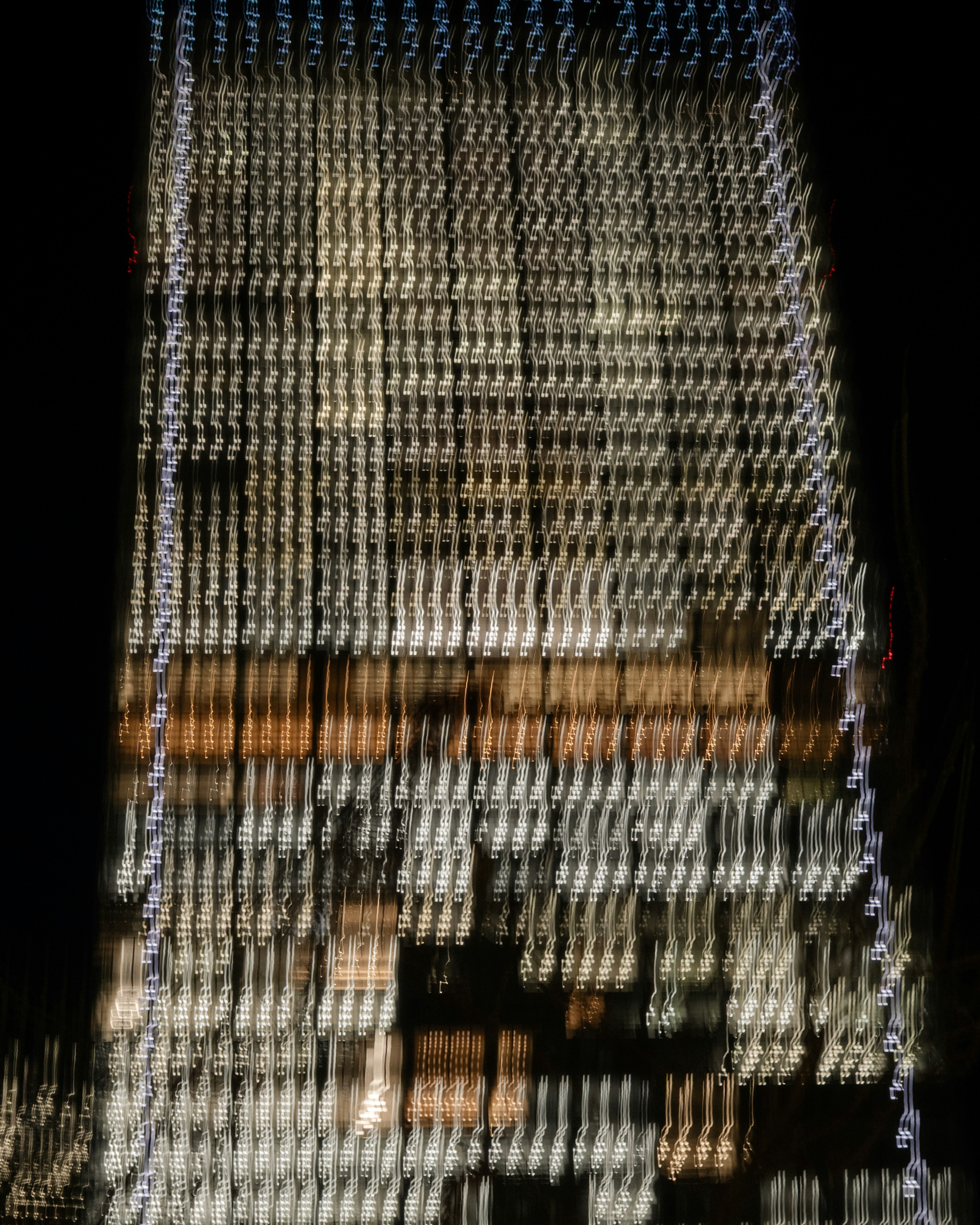 Blurred night view of a building facade illuminated with bright lights