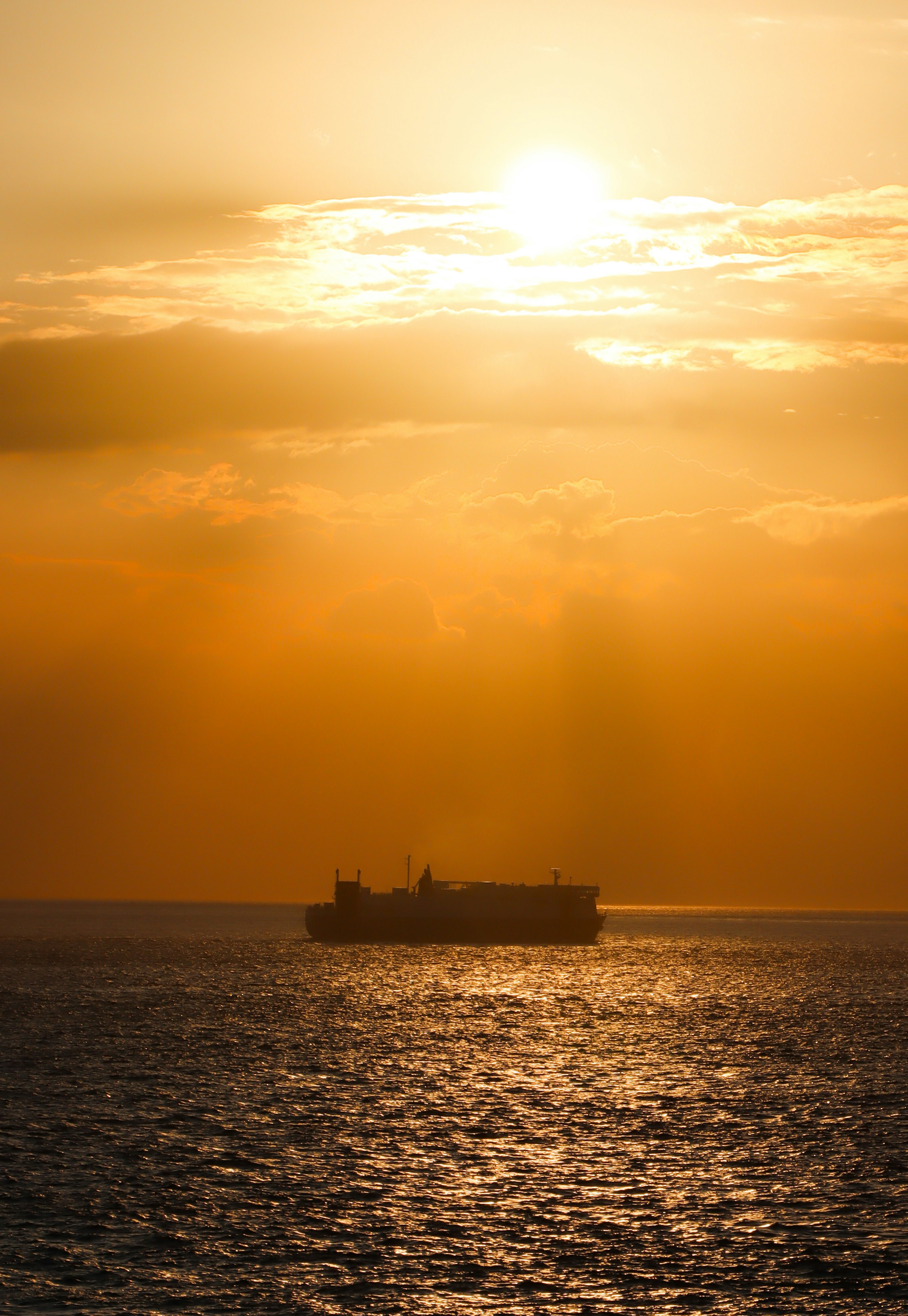 Cargo ship silhouetted against a vibrant sunset over the ocean