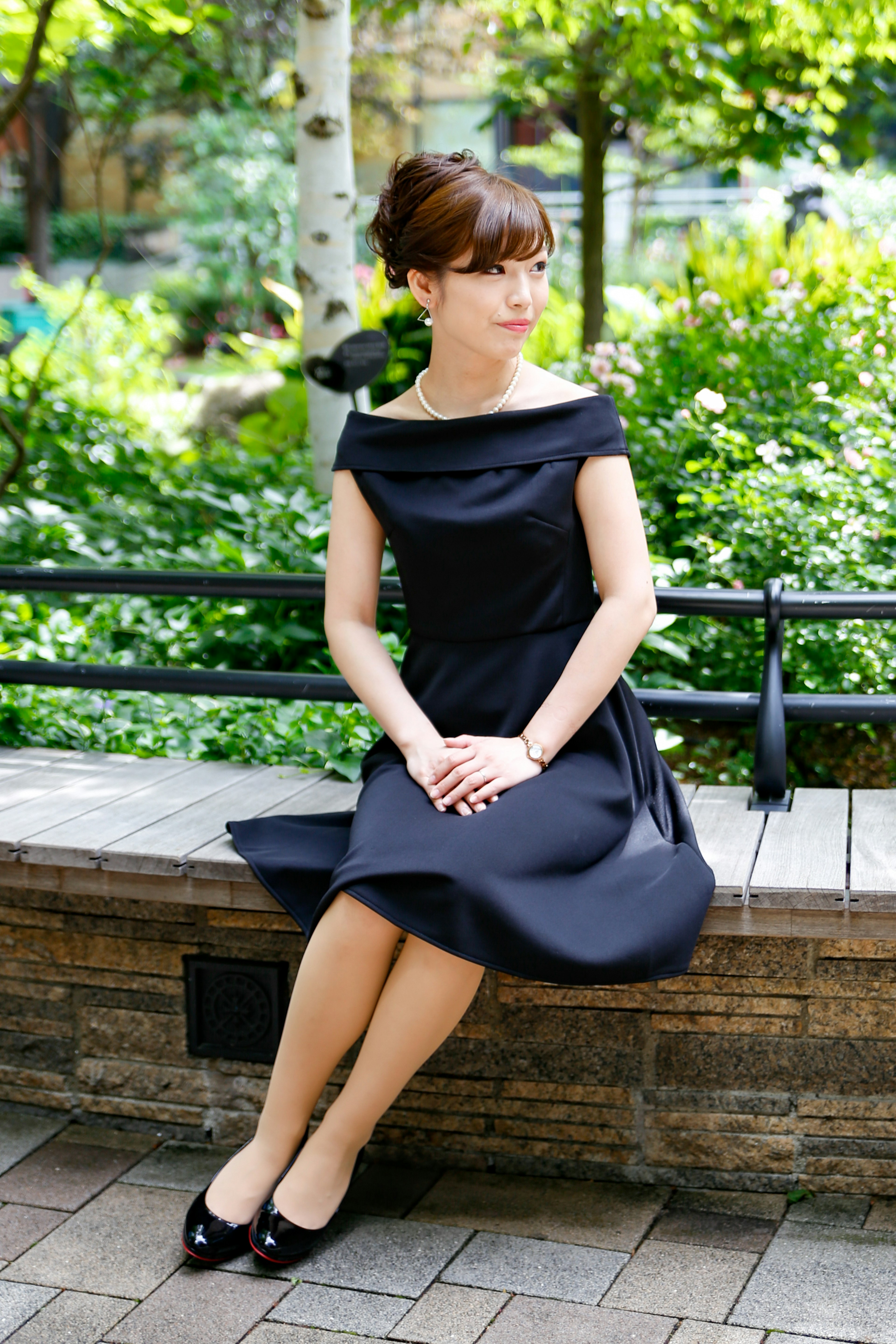 A woman in a black dress sitting on a park bench