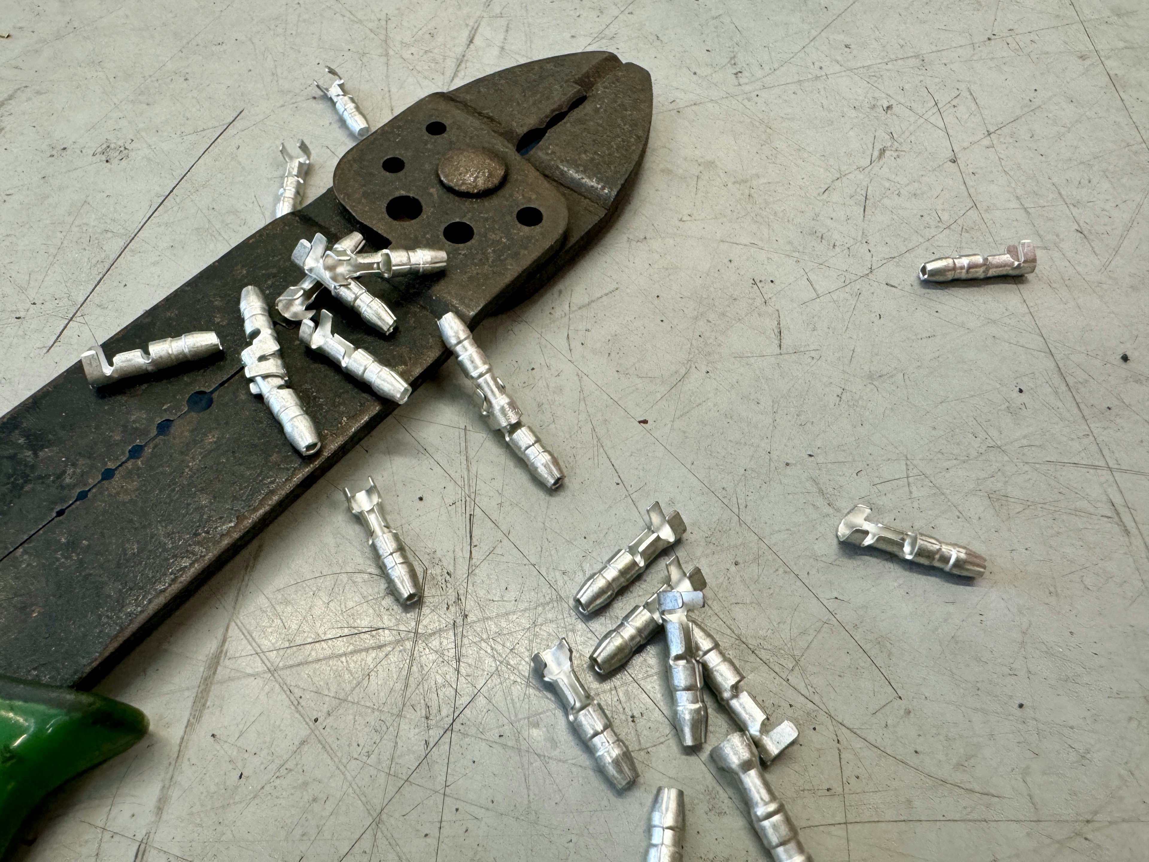 Metal crimp connectors and pliers are on a workbench