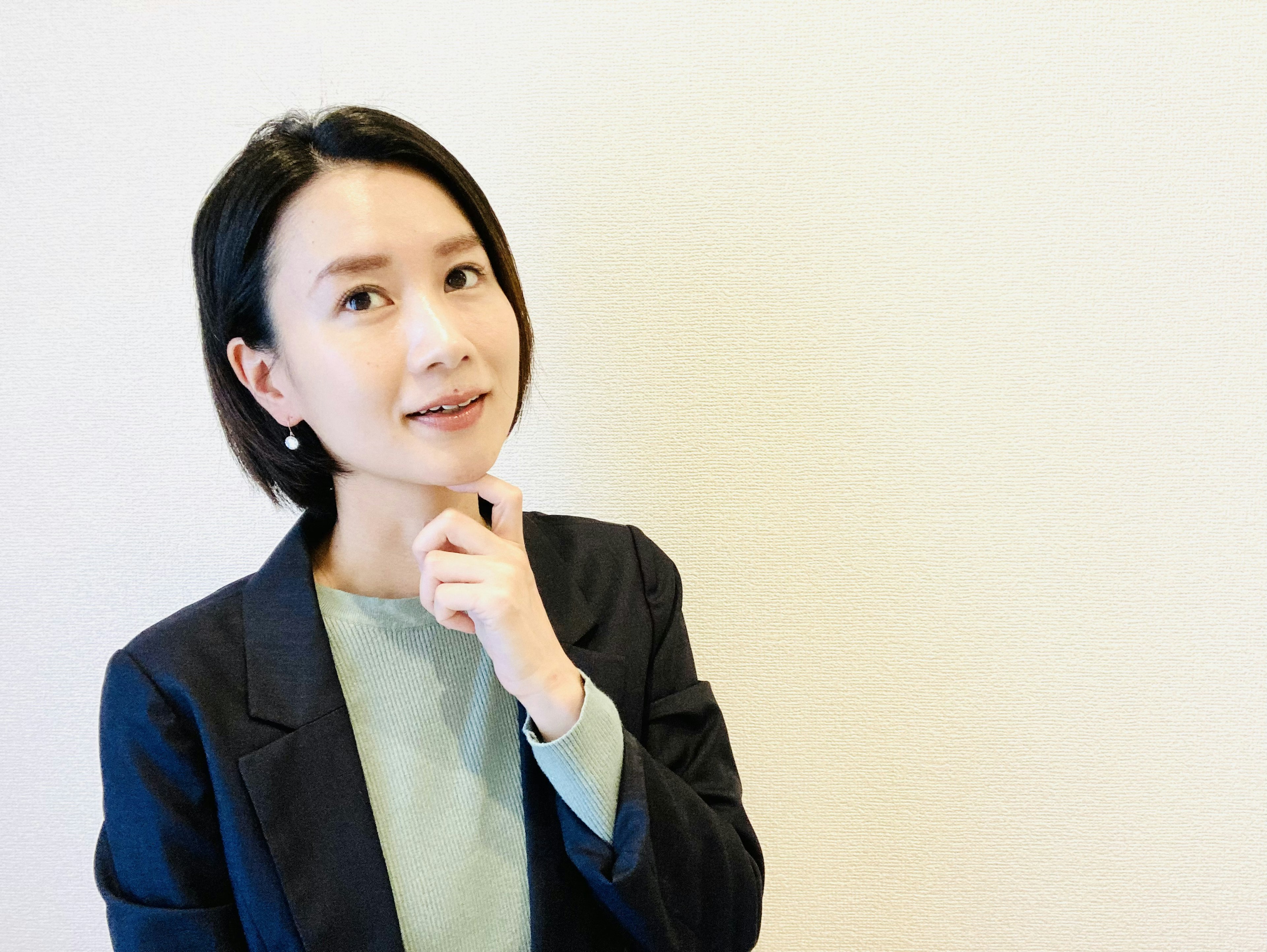 A woman in business attire posing thoughtfully with a subtle smile