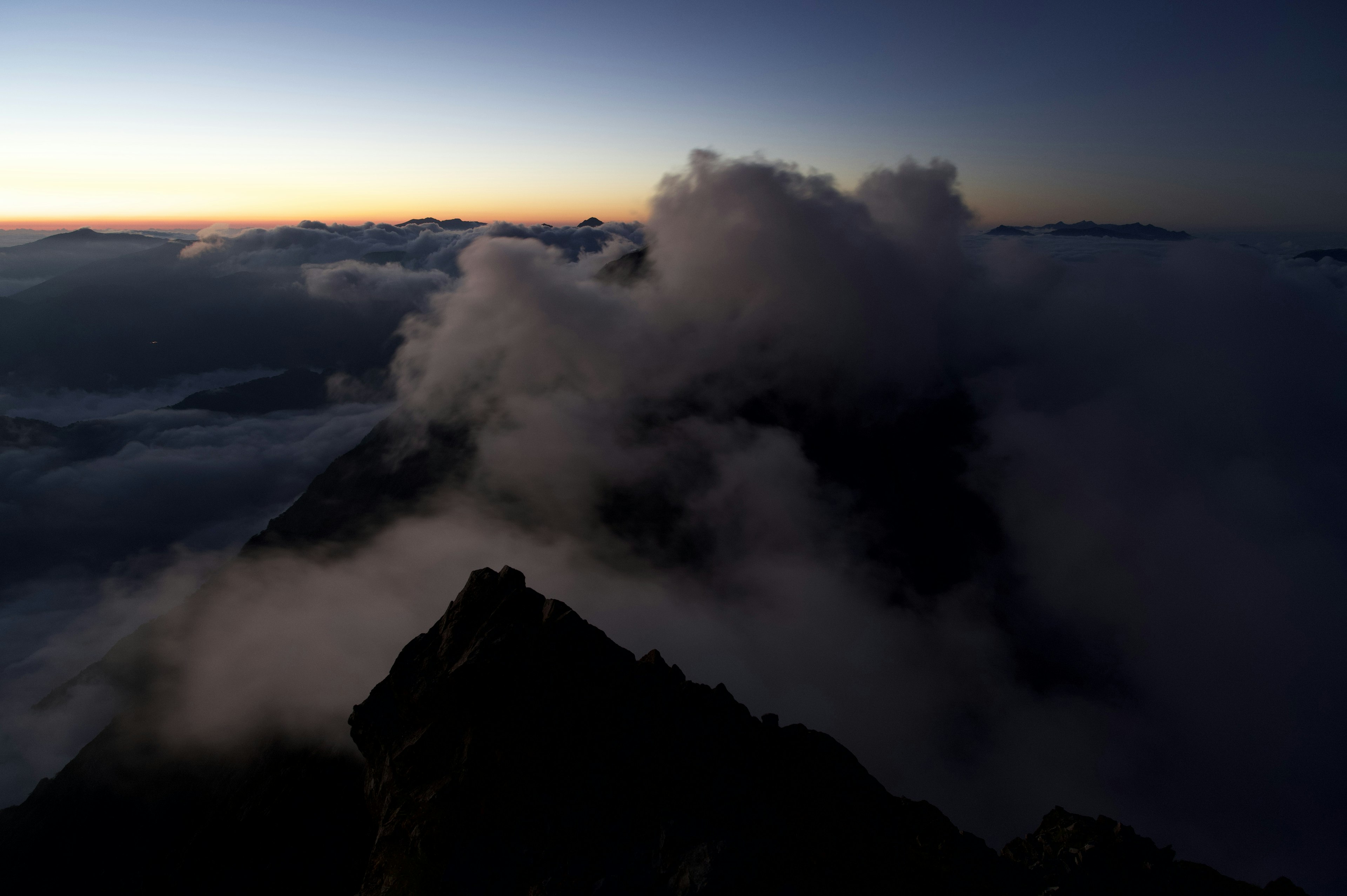 Silhouetted mountains shrouded in mist with dawn light