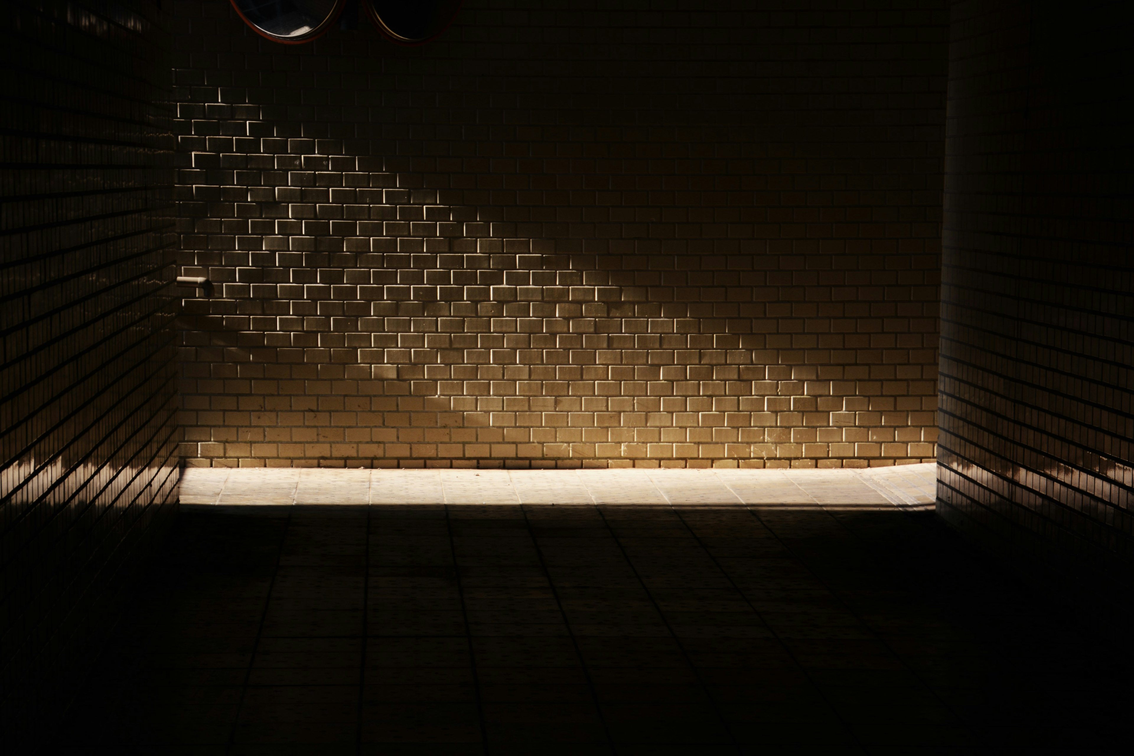 Light streaming into a dark space revealing textured brick wall