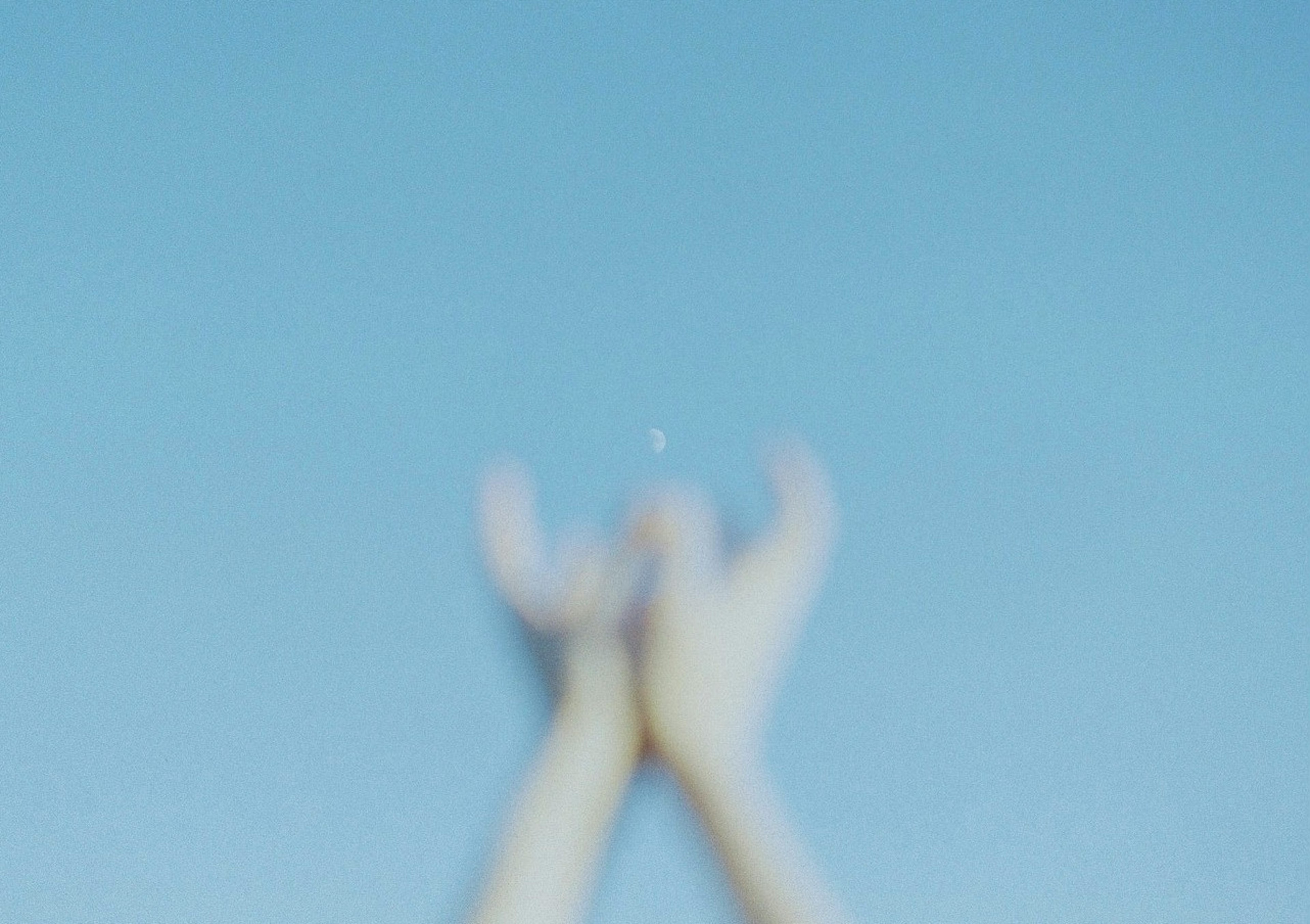 Blurred image of hands coming together under a blue sky