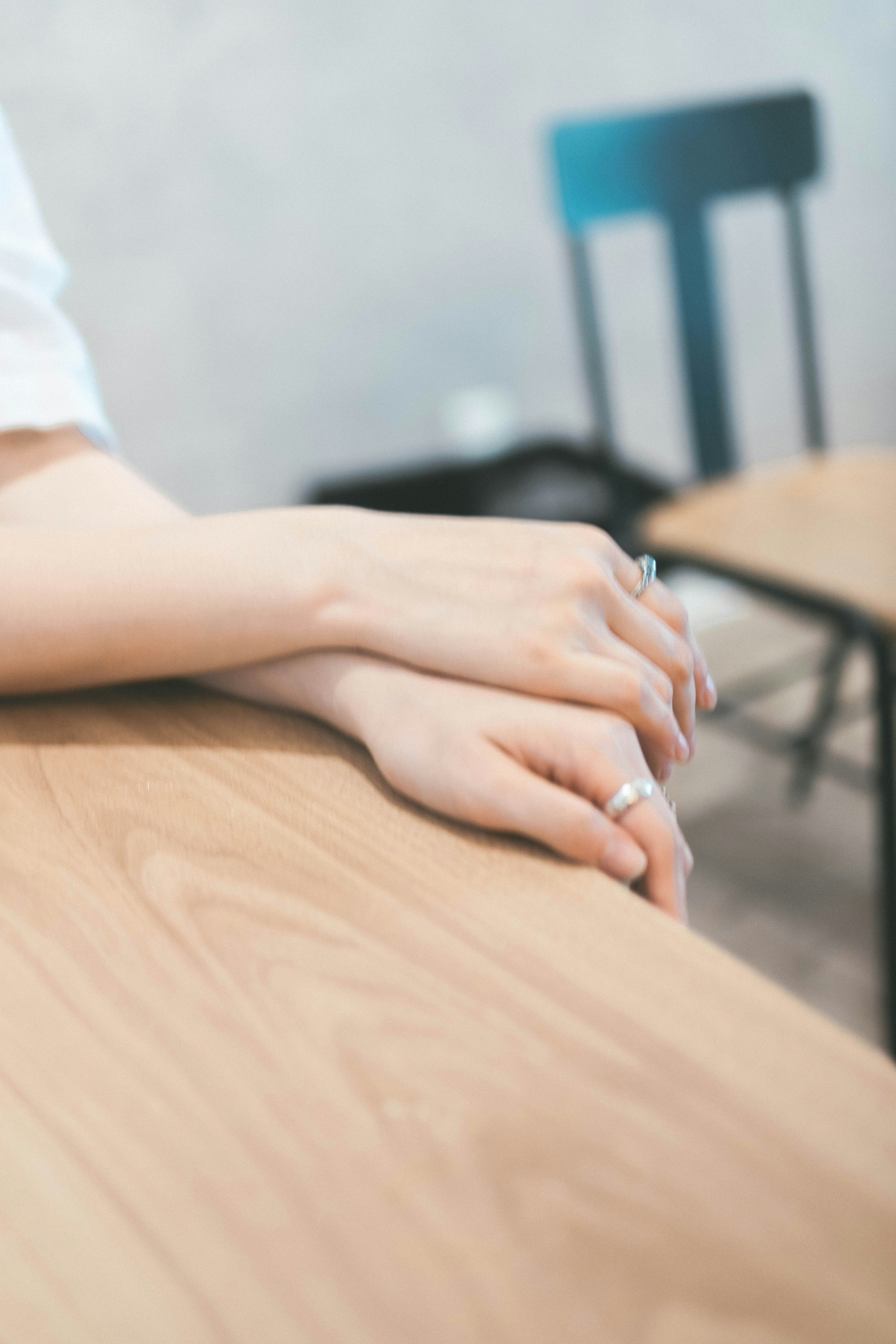 Manos descansando sobre una mesa de madera con un anillo en un dedo